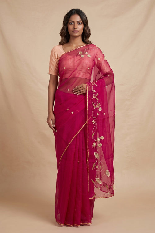 Model wearing a Bahar, crafted in silk organza, features delicate pani-zari enriched with zardozi, gota work, and dabka embroidery. Its defining element is an off-center floral vine running vertically through the body, breaking symmetry with quiet intent. Inspired by Art Nouveau?s flowing lines, the vine is rendered in slender leaves, zari chain-stitched stems, and alternating gota and zardozi flowers. The pallu trails gently onto the body in scattered embroidered blooms.