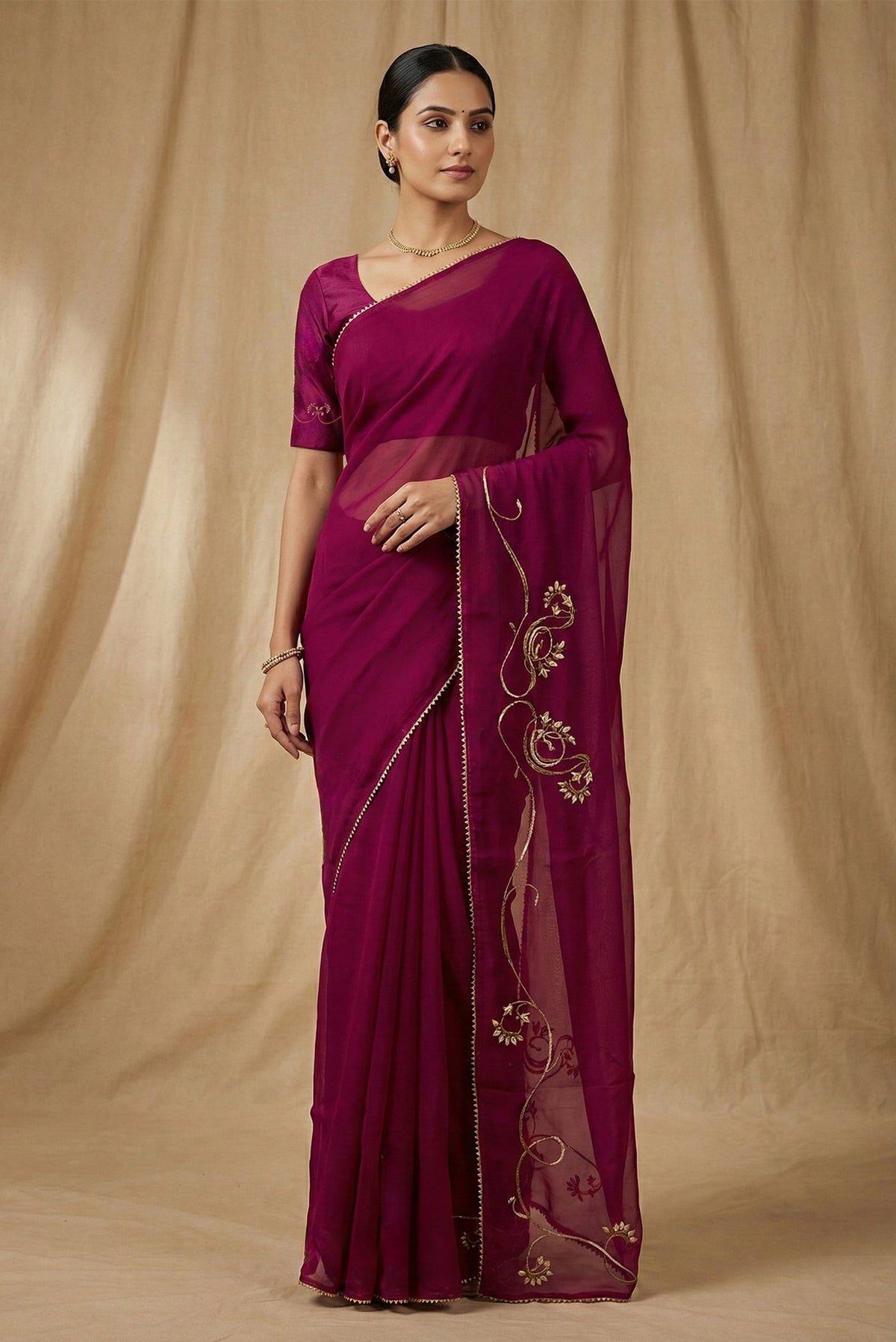 Model wearing a In Mira, pure silk organza becomes a canvas for antique gold and pani zari, brought to life through fine dabka and aari embroidery The pallu takes inspiration from the bull masks of the Cameroon Grasslands, translating their powerful curves into graceful motifs layered with florals and Art Nouveau lines Dual-tone zari and detailed shoulders lend the saree depth, movement, and a refined festive glow