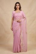 Model wearing a Meher, crafted in silk organza, is hand-embroidered with gold and antique-gold zardozi. Organic vines and floral buds form a rich border that meets at a delicate fan motif - an ornamental form celebrated in late 19th and early 20th century Art Nouveau design. Iris flowers, symbolising femininity, grace, and mystique, echo the saree?s fluid curves as the motif repeats across the body, finished with elegant gota edges.