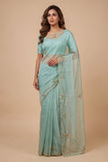 Model wearing a Meher, crafted in silk organza, is hand-embroidered with gold and antique-gold zardozi. Organic vines and floral buds form a rich border that meets at a delicate fan motif - an ornamental form celebrated in late 19th and early 20th century Art Nouveau design. Iris flowers, symbolising femininity, grace, and mystique, echo the saree?s fluid curves as the motif repeats across the body, finished with elegant gota edges.