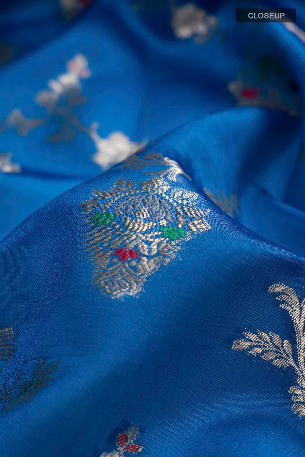 Close up of Blue Banarasi Raw Silk Saree with Zari Butta on the body and Zari Border displaying folds