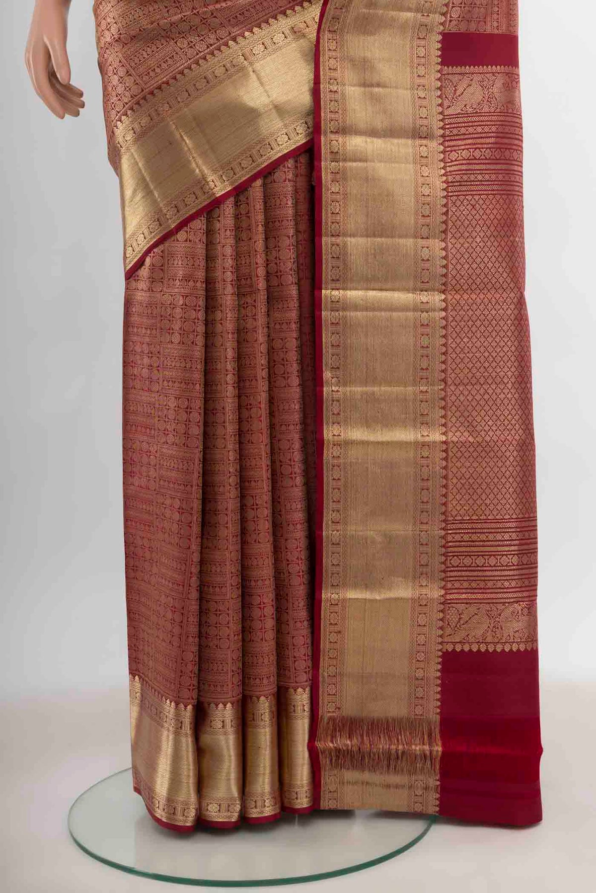 Pleats and pallu of Maroon Kanchipuram Silk Saree with Zari Butta on the body and Silk Border. 