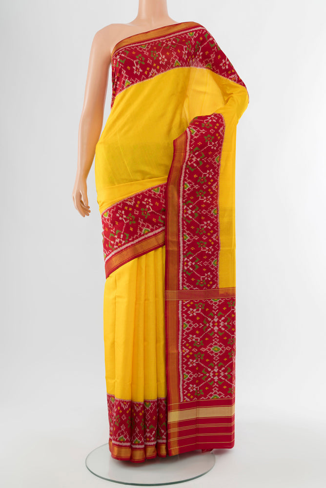 Yellow Rajkot Patola Silk Saree with Ikat Print on the body and Silk Border.  displayed on a mannequin
