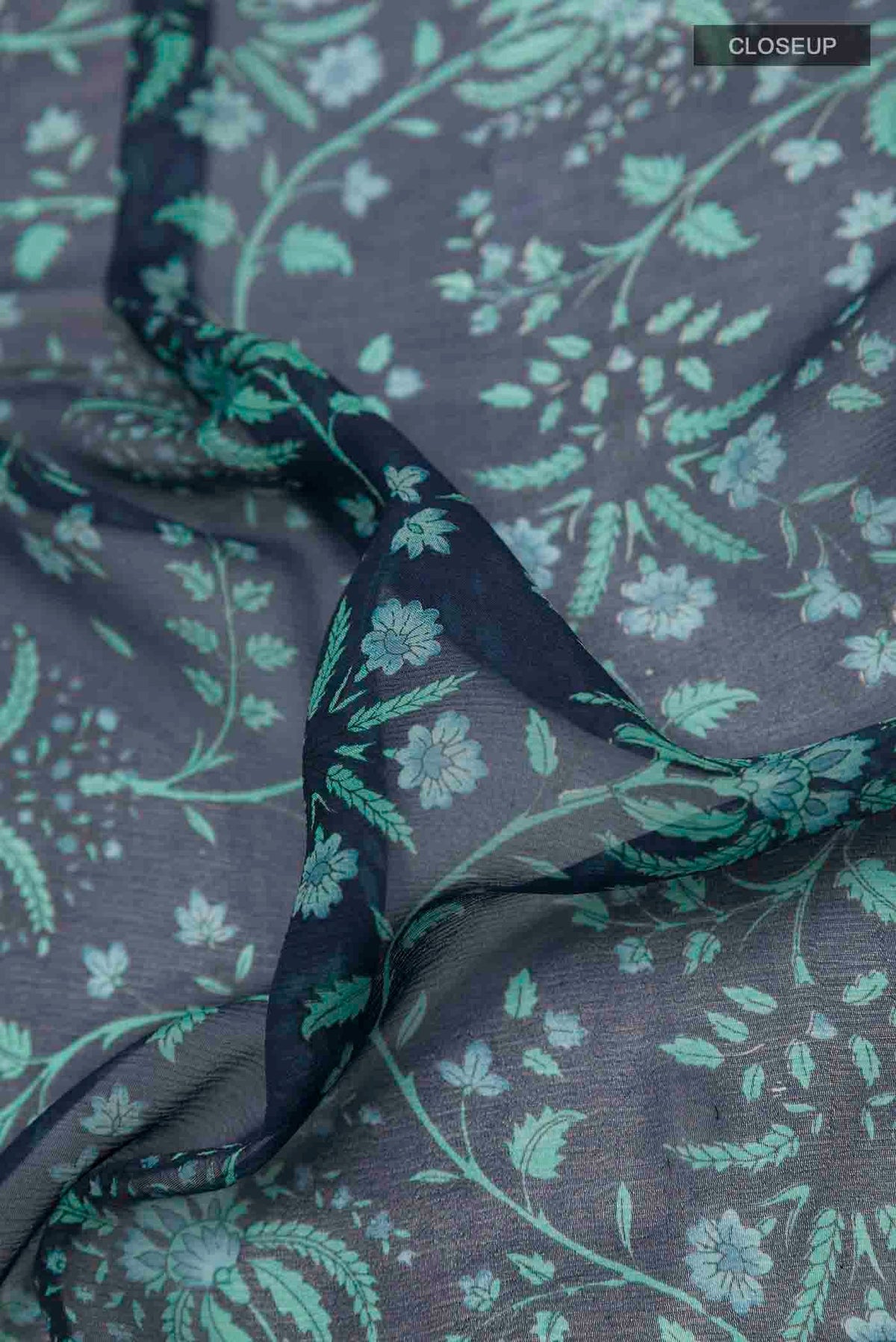Close up of Peacock Blue Mysore Chiffon Saree with Printed design on the body and Zari Border displaying folds