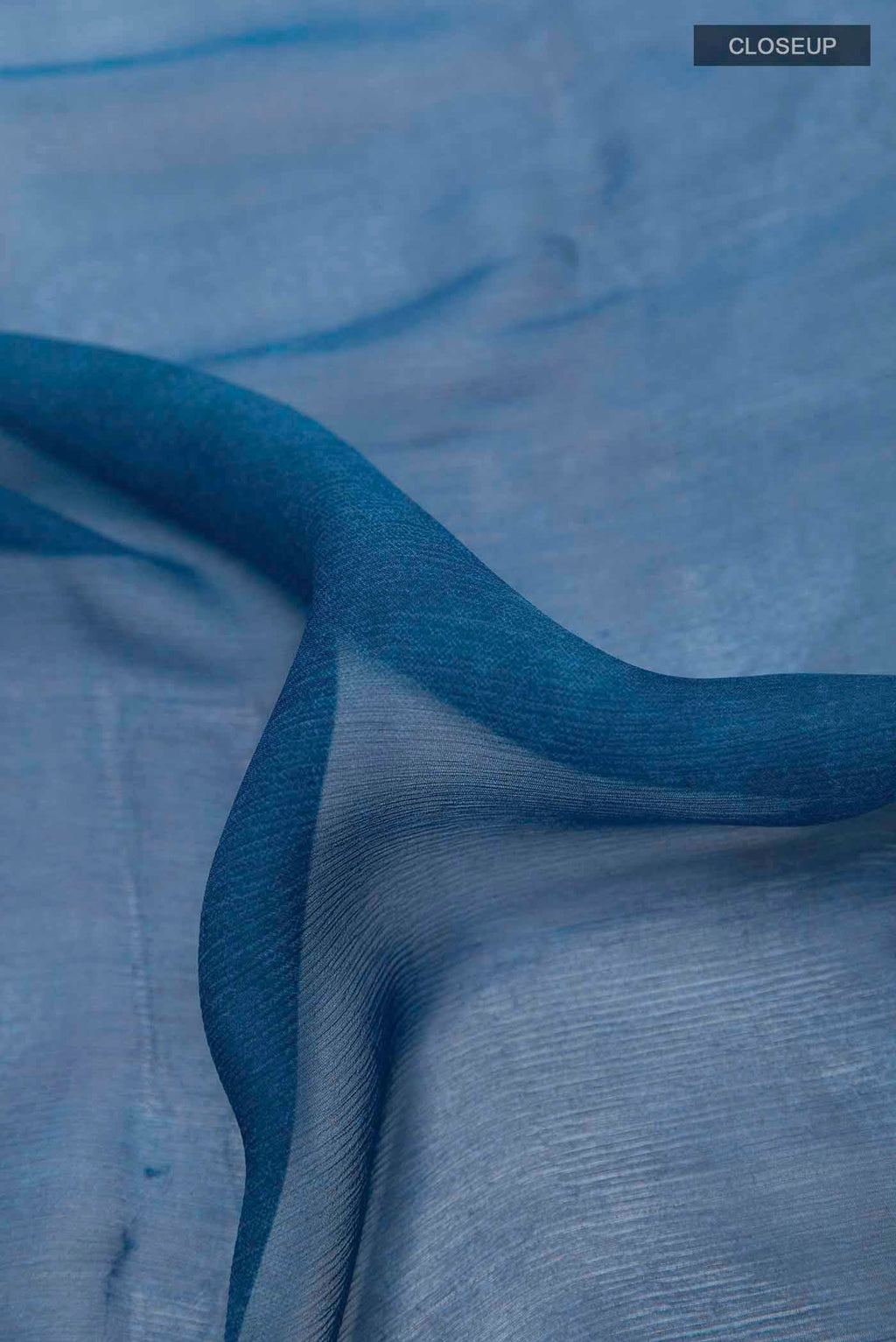 Close up of Peacock Blue Mysore Chiffon Saree with Printed design on the body and Zari Border displaying folds