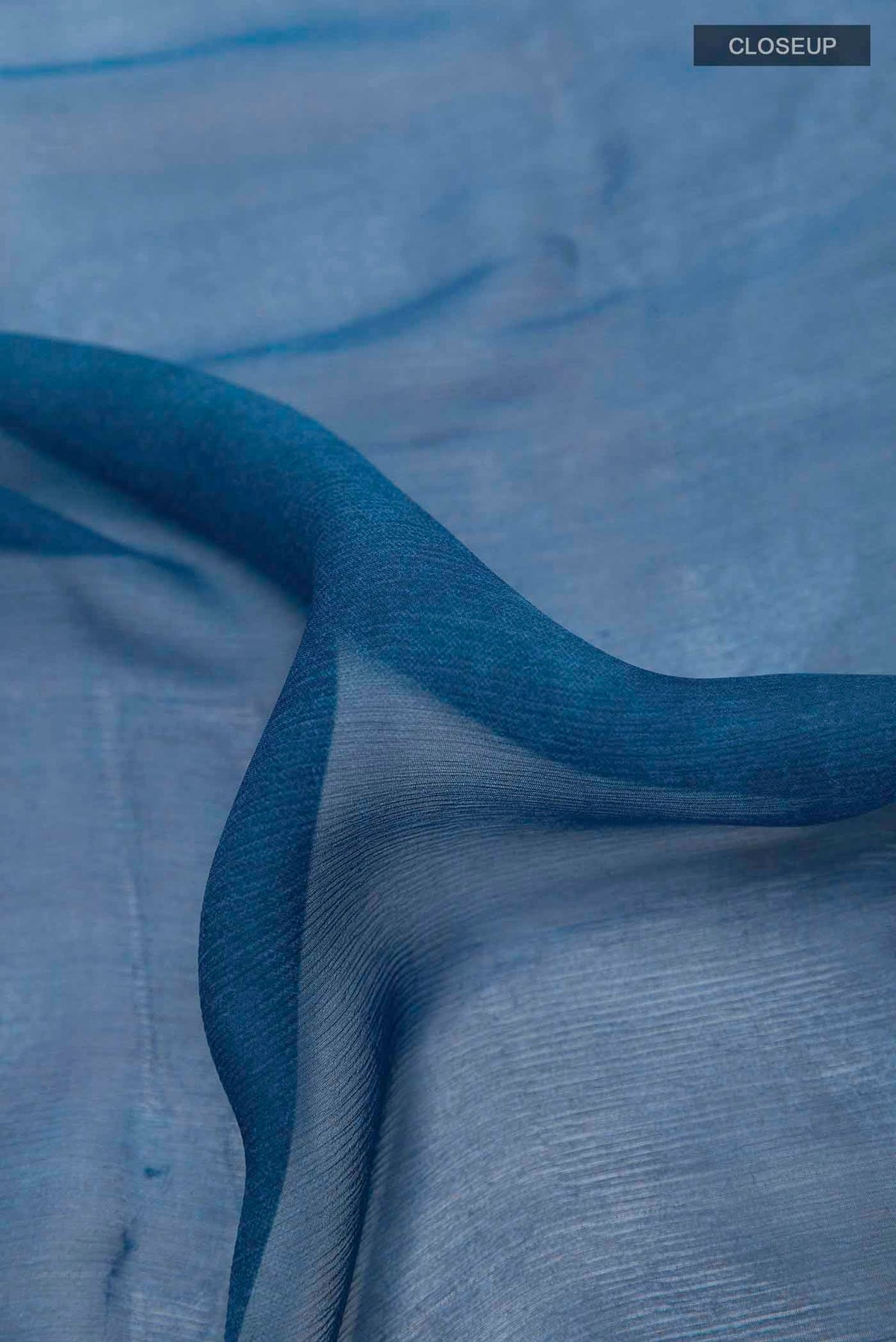 Close up of Peacock Blue Mysore Chiffon Saree with Printed design on the body and Zari Border displaying folds