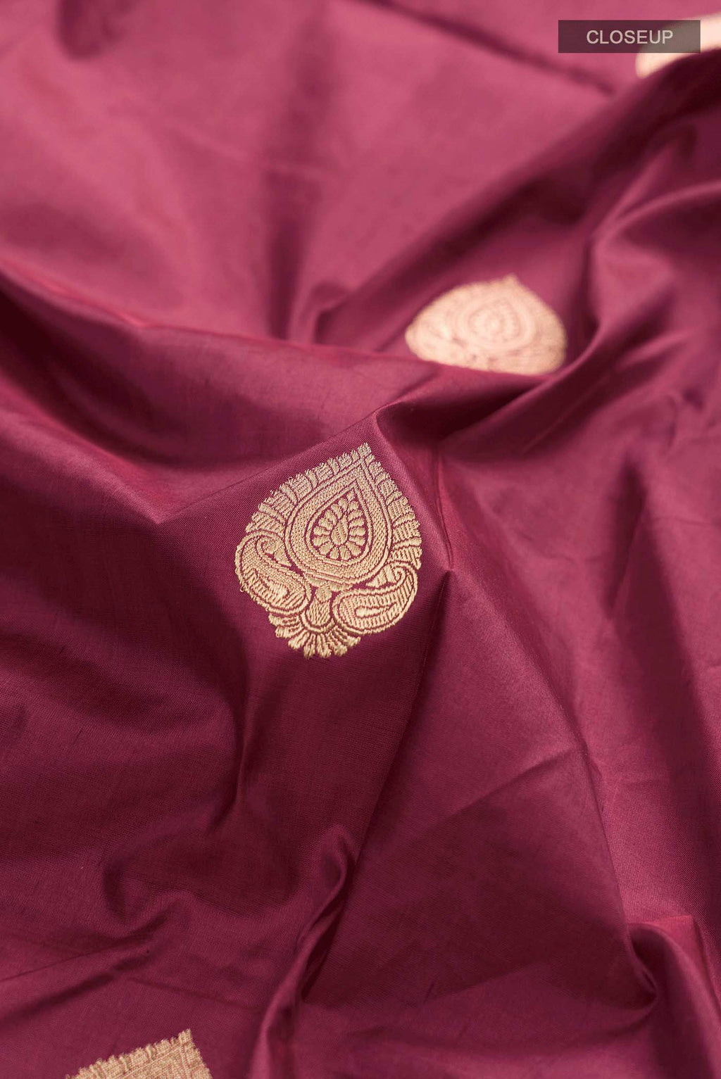 Close up of Maroon Banarasi Katan Silk Saree with Zari Butta on the body and Zari Border displaying folds