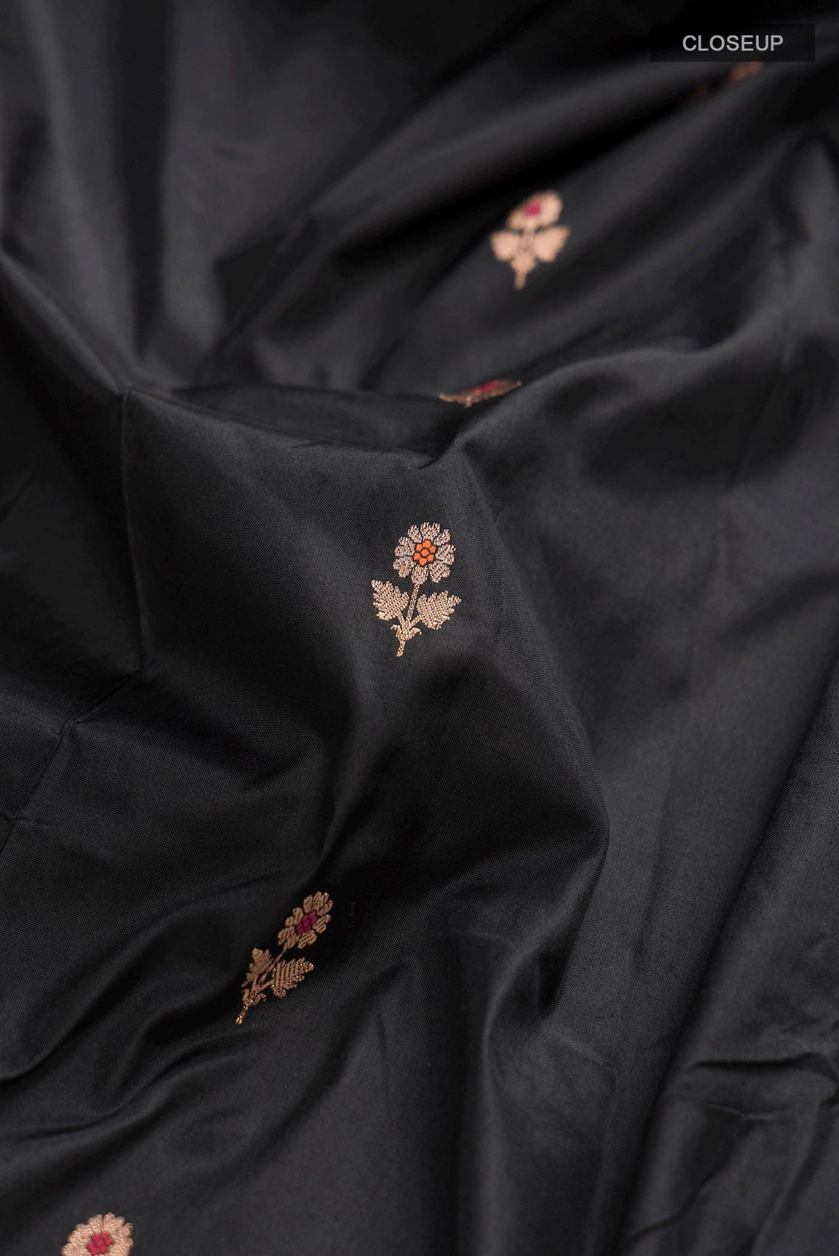Close up of Black Banarasi Katan Silk Saree with Zari Butta on the body and Zari Border displaying folds