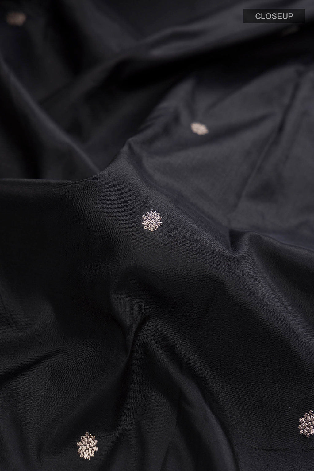 Close up of Black Banarasi Katan Silk Saree with Zari Butta on the body and Zari Border displaying folds