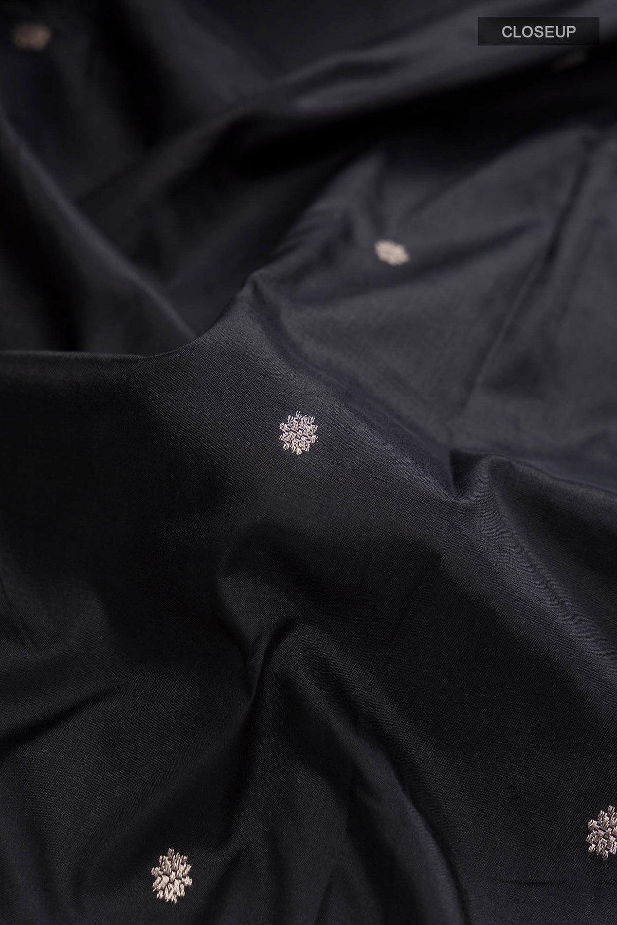 Close up of Black Banarasi Katan Silk Saree with Zari Butta on the body and Zari Border displaying folds