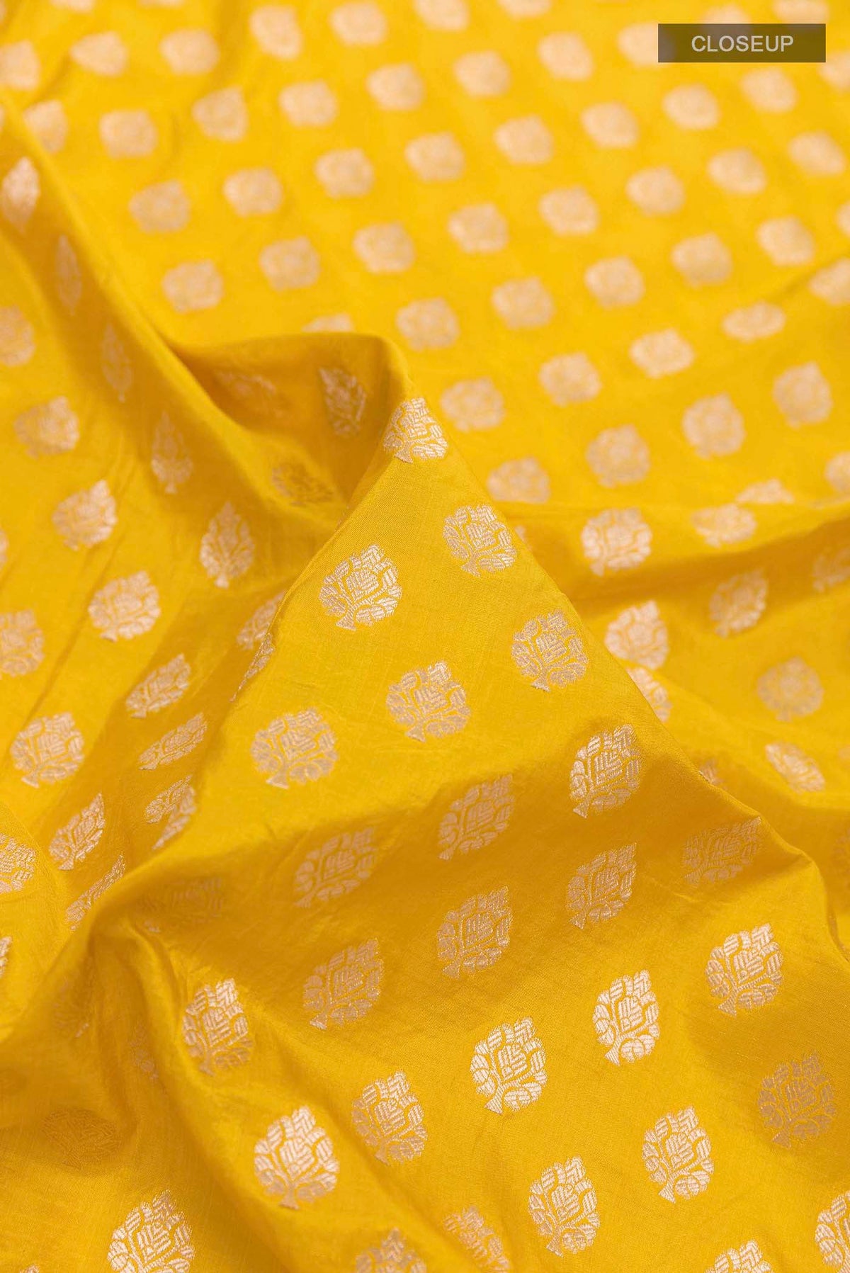 Close up of Yellow Banarasi Silk Saree with Zari Butta on the body and Sequin Border displaying folds