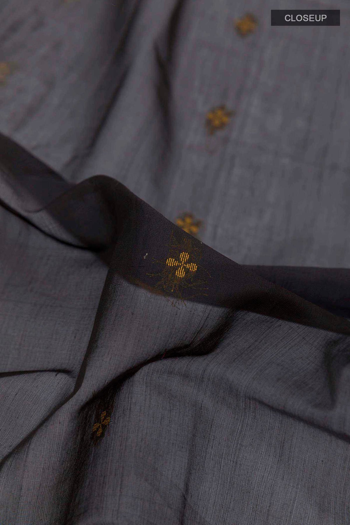 Close up of Black Blended Kora Cotton Saree with Zari And Thread Butta on the body and Zari Border displaying folds