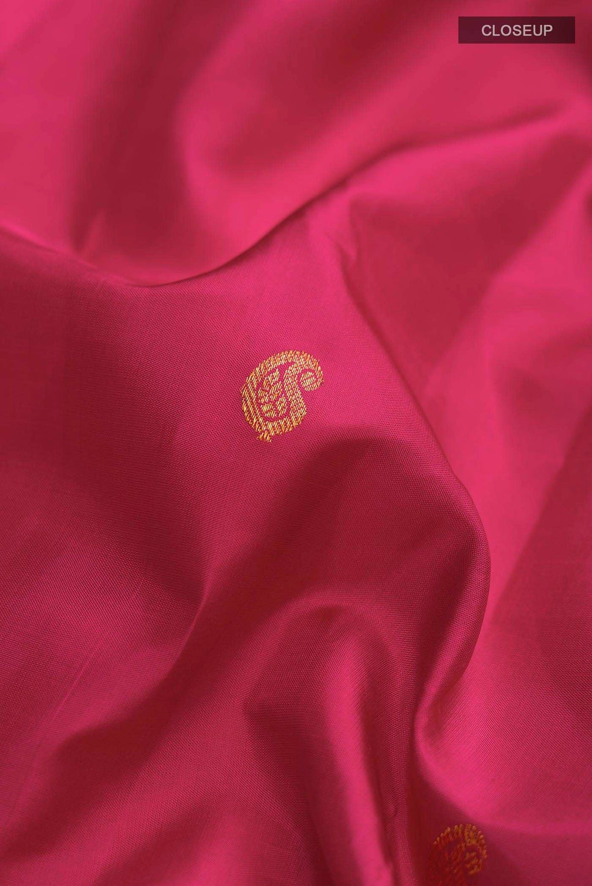 Close up of Pink Kanchipuram Silk Saree with Zari Butta on the body and Zari Border displaying folds