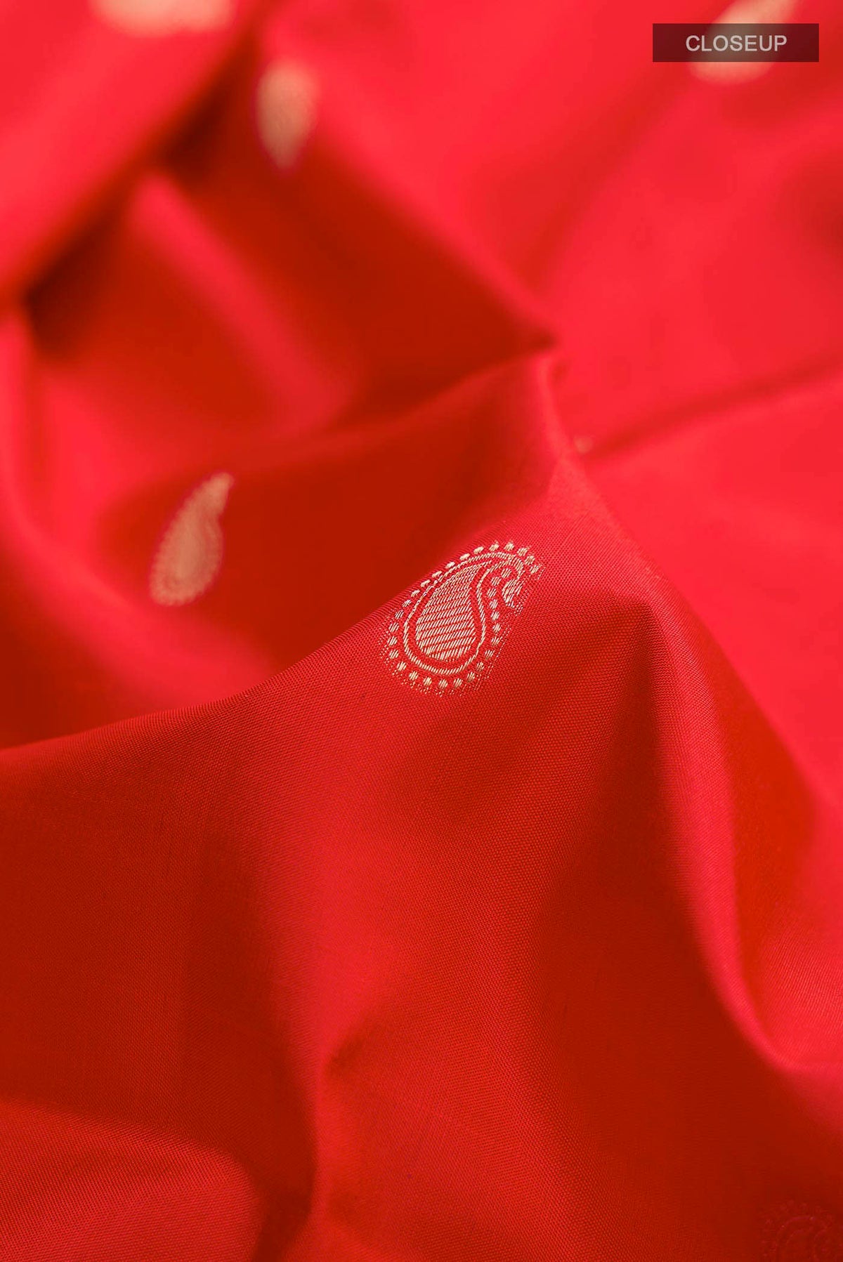 Close up of Orange Soft Silk Saree with Zari Butta on the body and Zari Border displaying folds