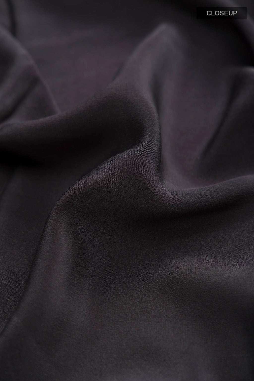 Close up of Black Crepe Saree with Printed design on the body and Plain Border displaying folds