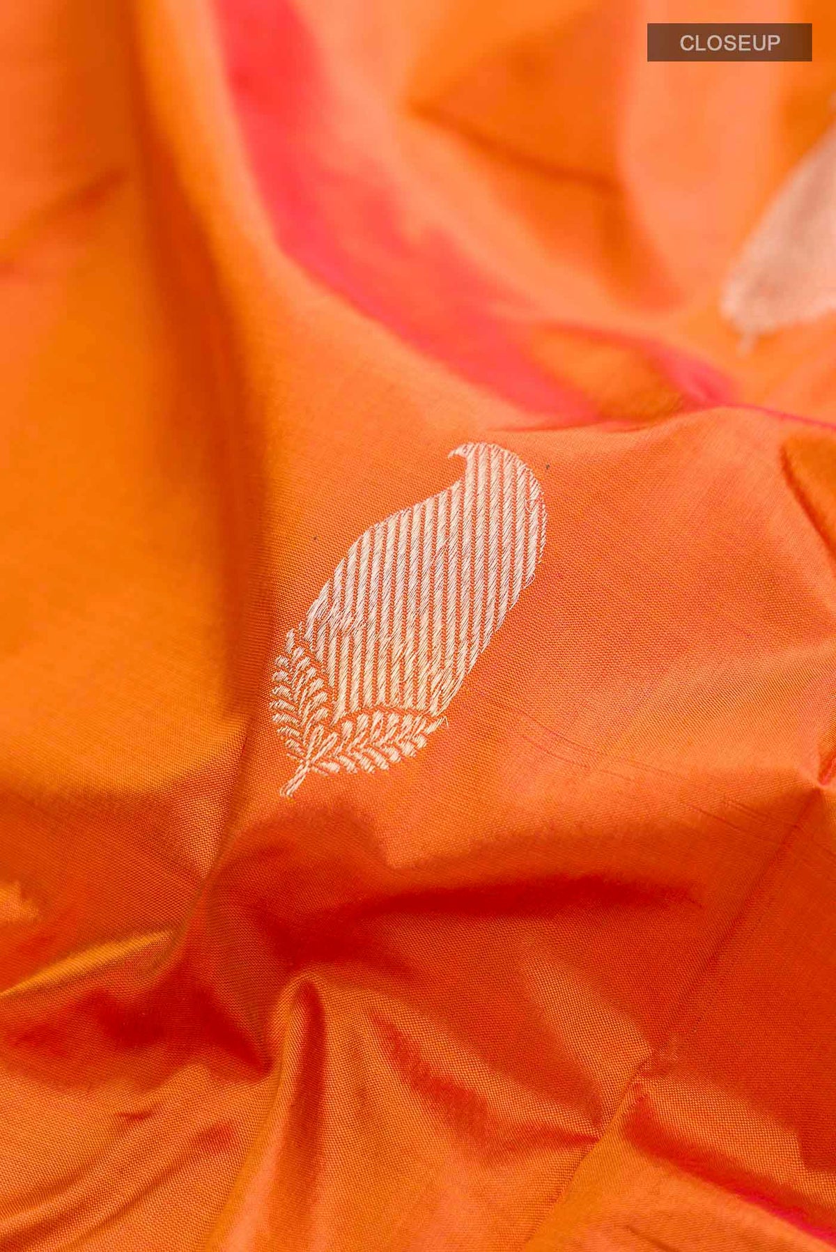 Close up of Orange Banarasi Katan Silk Saree with Zari Butta on the body and Zari Border displaying folds