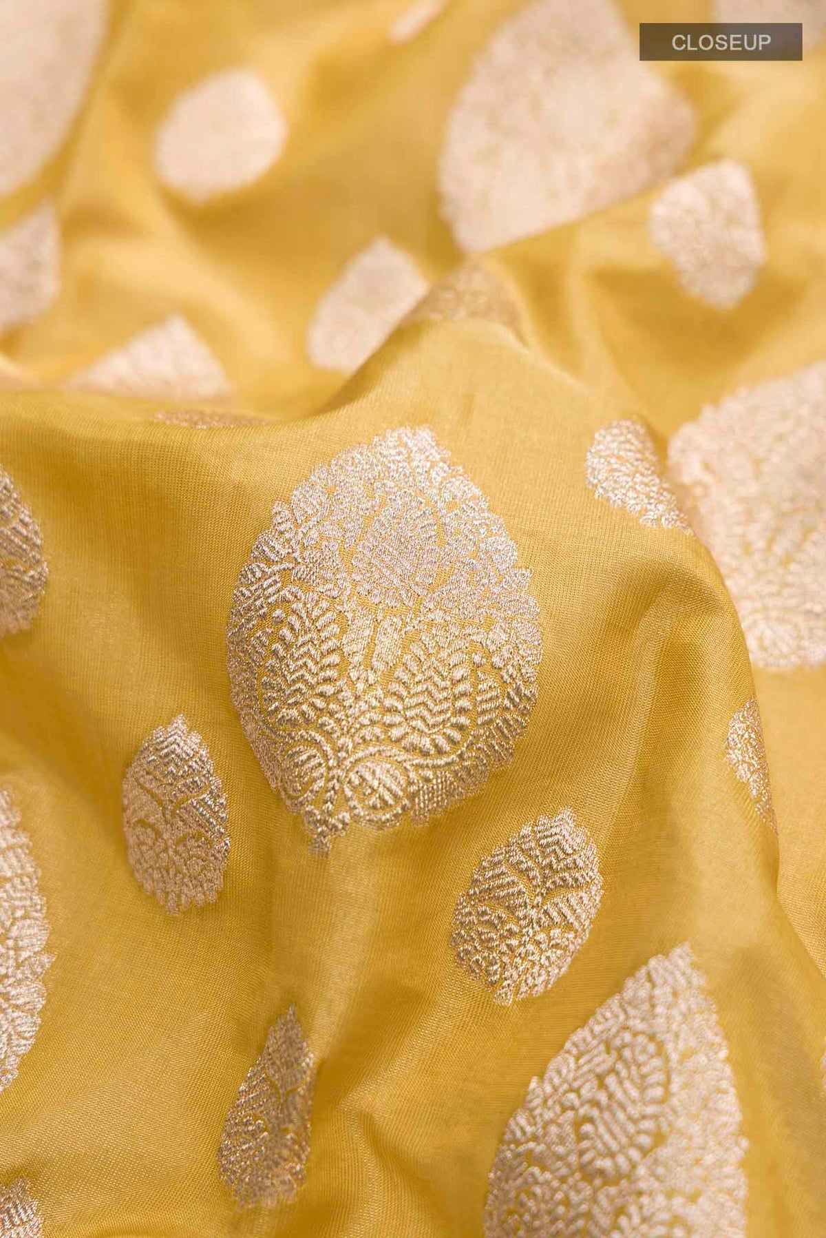 Close up of Yellow Banarasi Silk Saree with Zari Butta on the body and Zari Border displaying folds