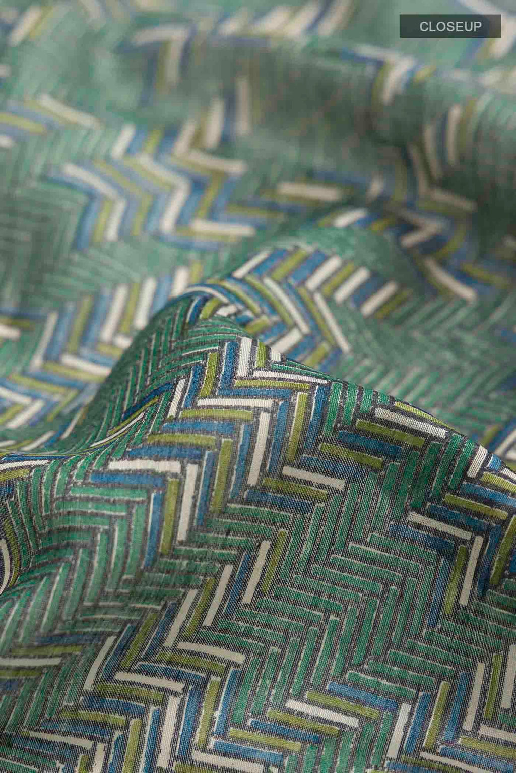 Close up of Green Tussar Silk Saree with Printed design on the body and Zari Border displaying folds