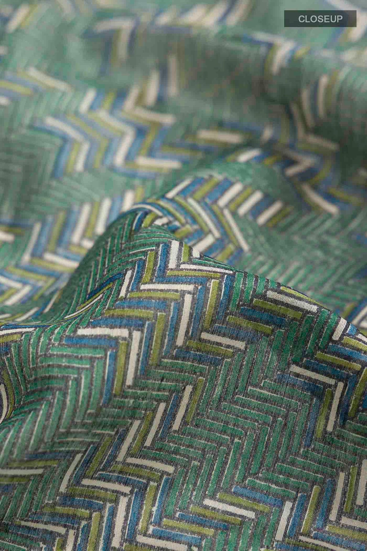 Close up of Green Tussar Silk Saree with Printed design on the body and Zari Border displaying folds