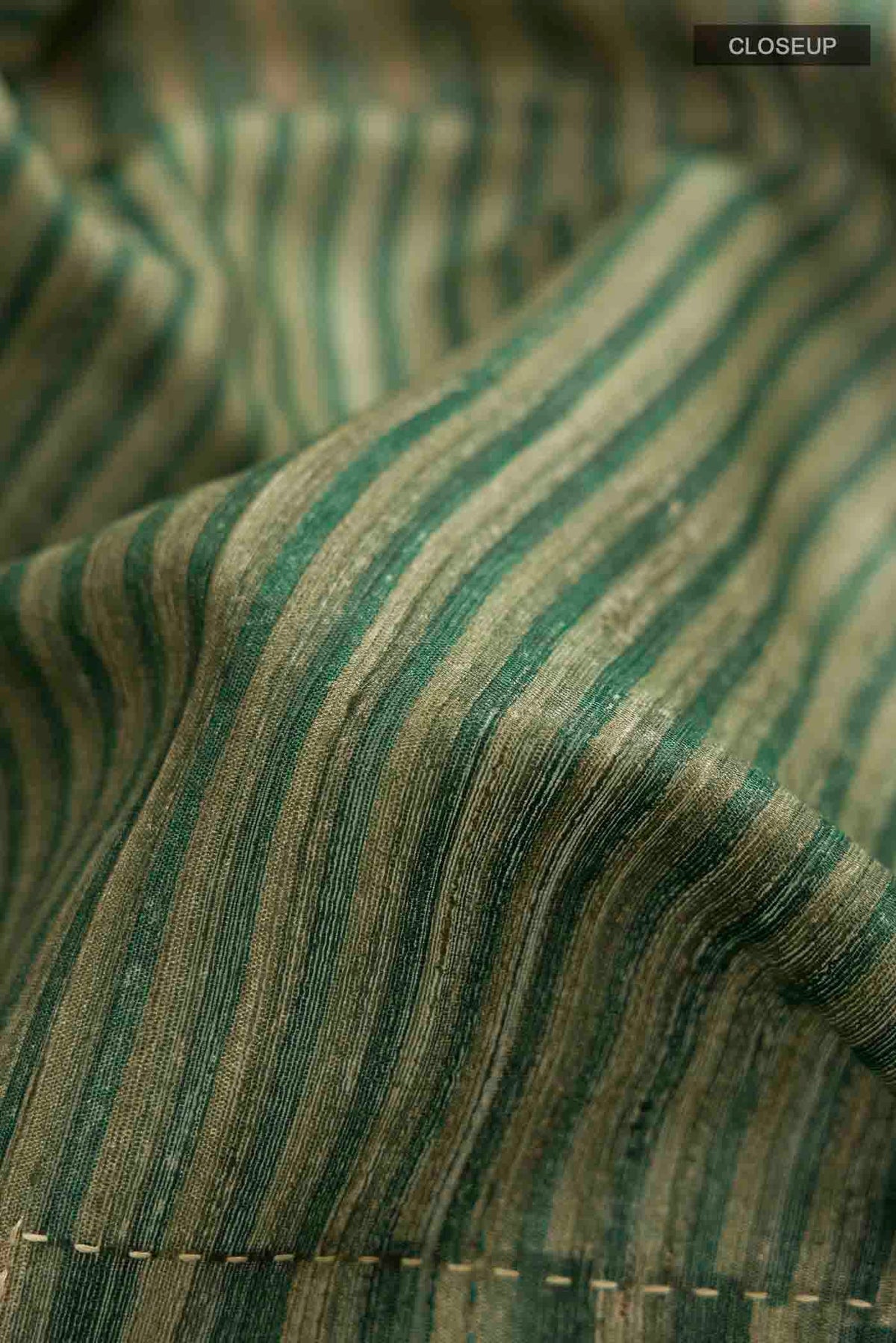 Close up of Green Tussar Silk Saree with Stripes on the body and Zari Border displaying folds