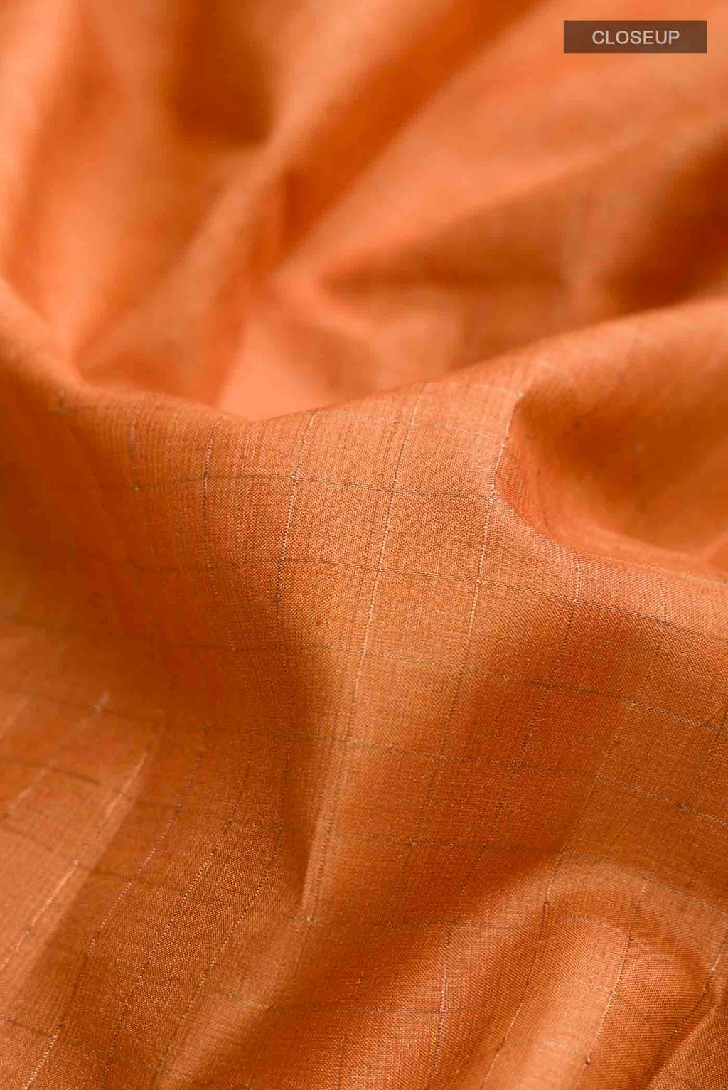 Close up of Orange Tussar Silk Saree with Checked design on the body and Printed Border displaying folds