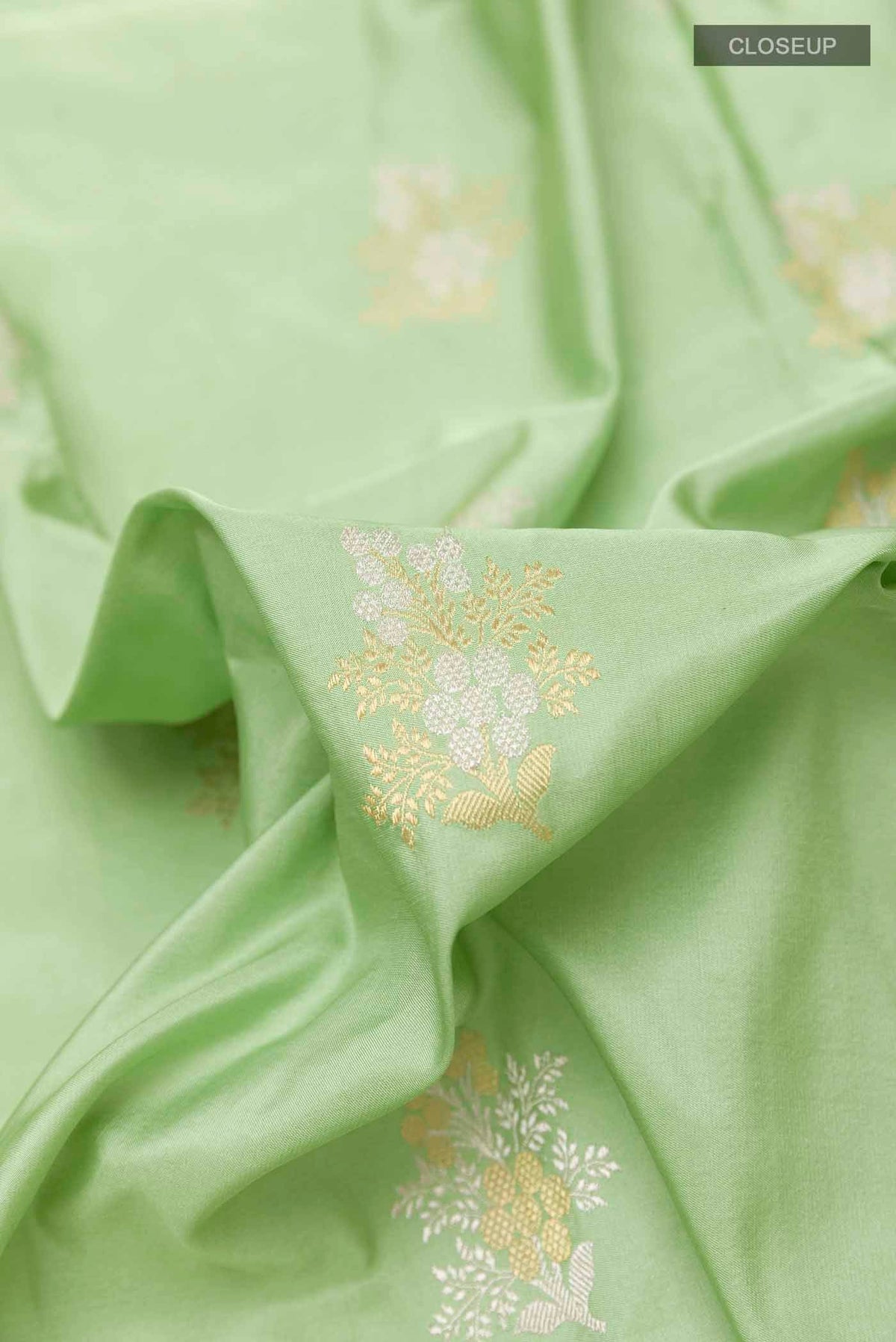 Close up of Green Banarasi Silk Saree with Zari Butta on the body and Zari Border displaying folds