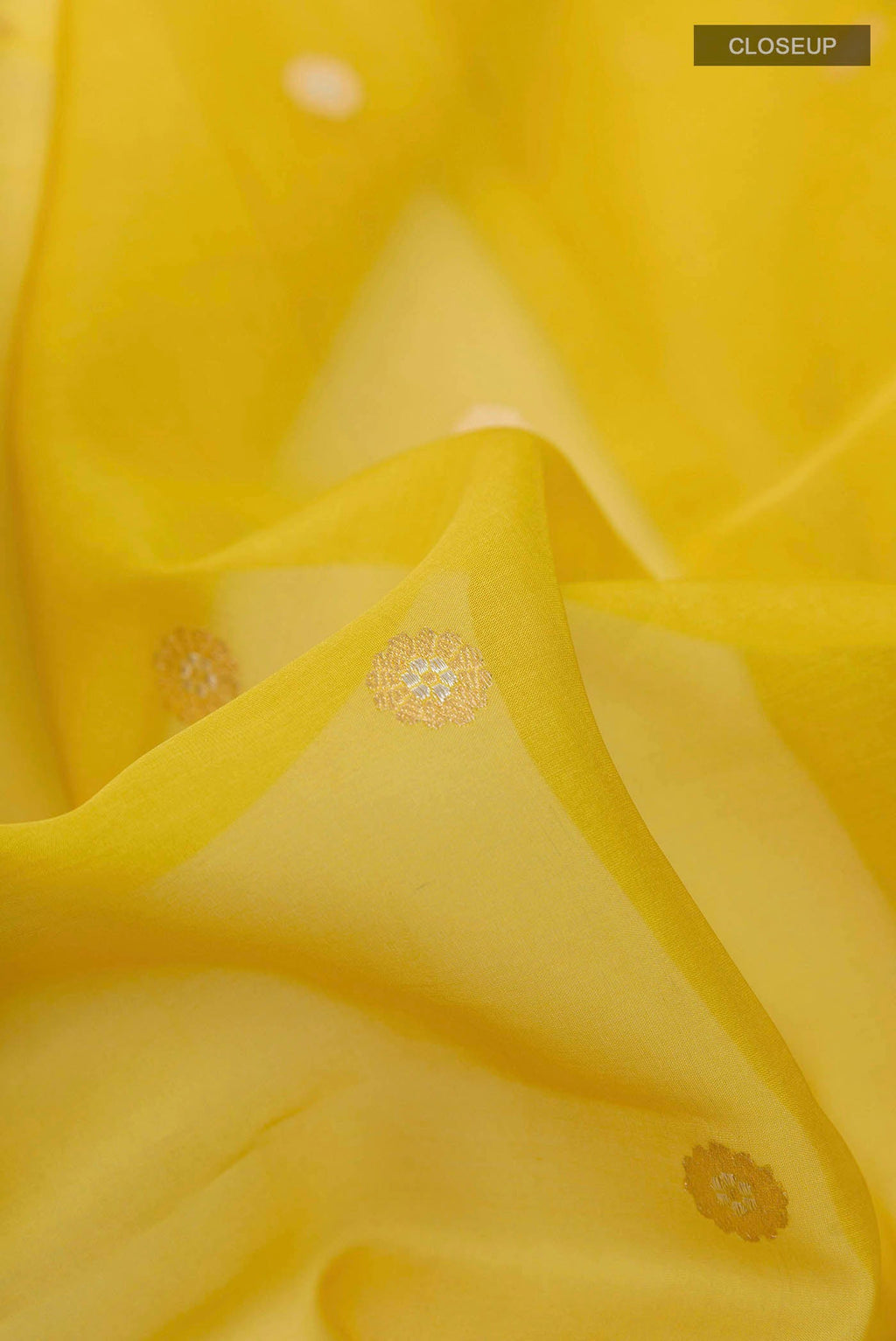 Close up of Yellow Banarasi Kora Silk Saree with Zari Butta on the body and Zari Border displaying folds
