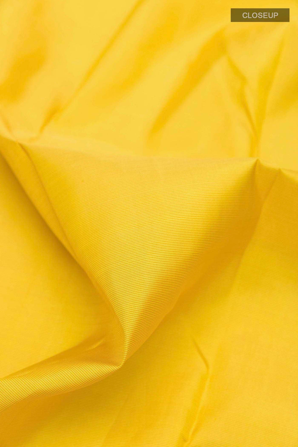Close up of Yellow Kanchipuram Silk Saree with Zari Butta on the body and Ganga Jamuna Border displaying folds