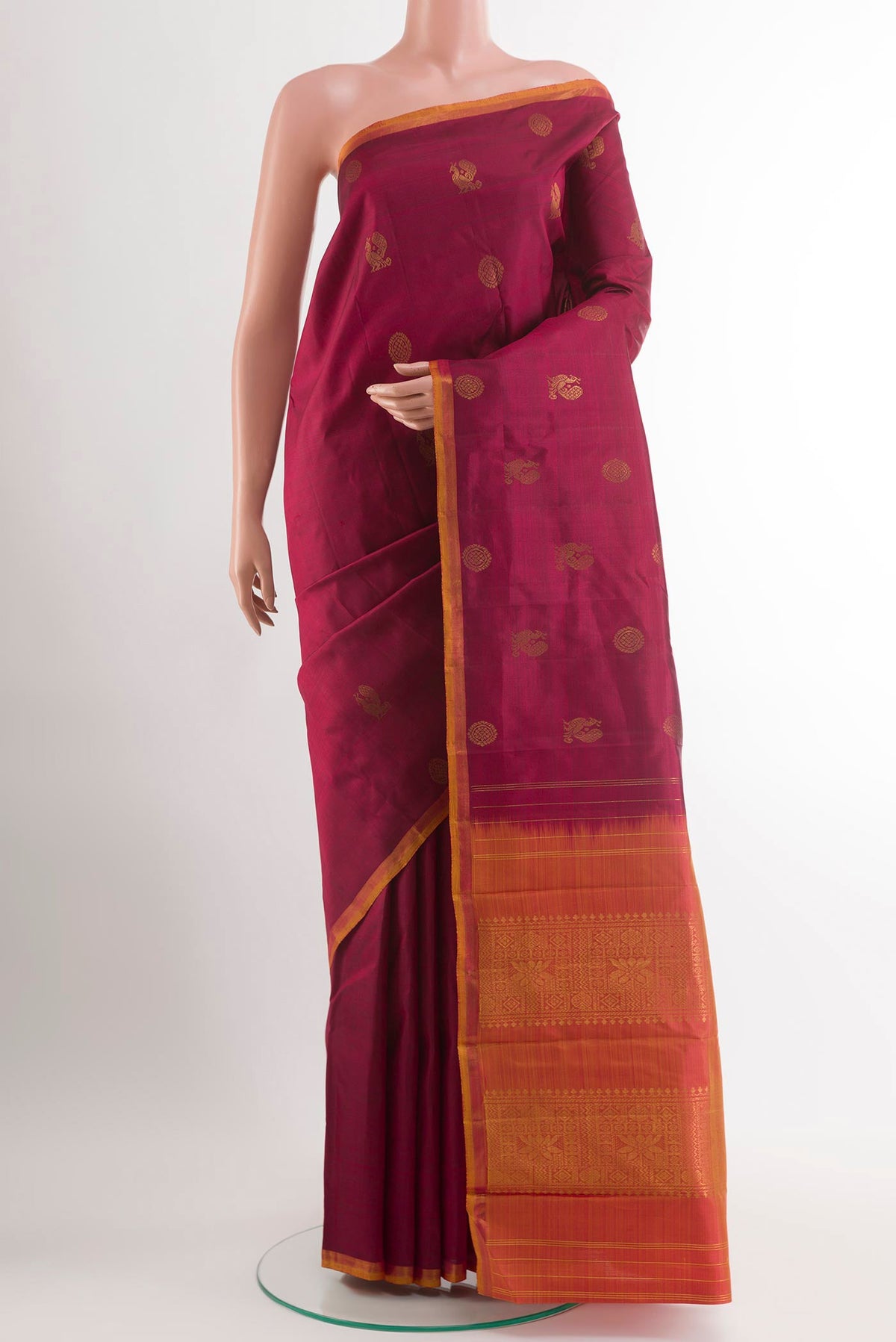 Maroon Kanchipuram Silk Saree with Zari Butta on the body and Zari Border.  displayed on a mannequin