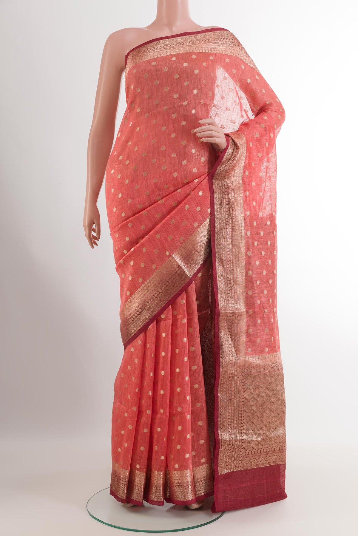 Coral Linen Saree with Zari Butta on the body and Zari Border.  displayed on a mannequin