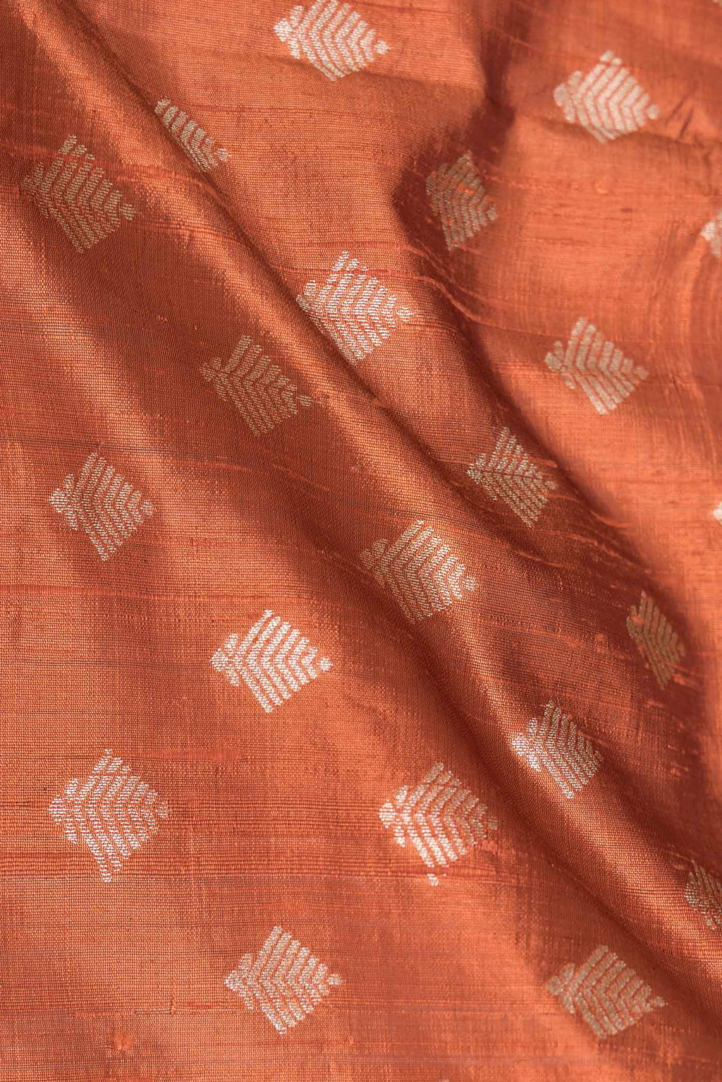 Close up of Brick Orange Dual Tone Raw Silk Saree with Zari Brocade on the body and Zari Border displaying folds