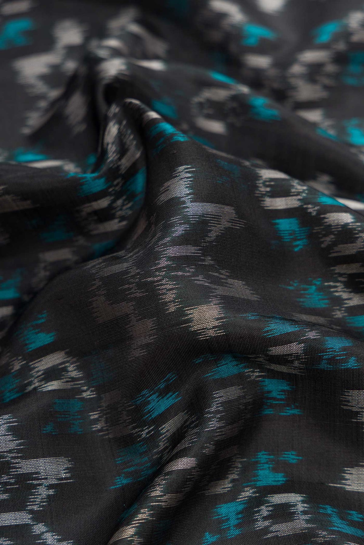 Close up of Black Dual Tone Soft Silk Saree with Ikat Print on the body and Zari Border.  displaying folds