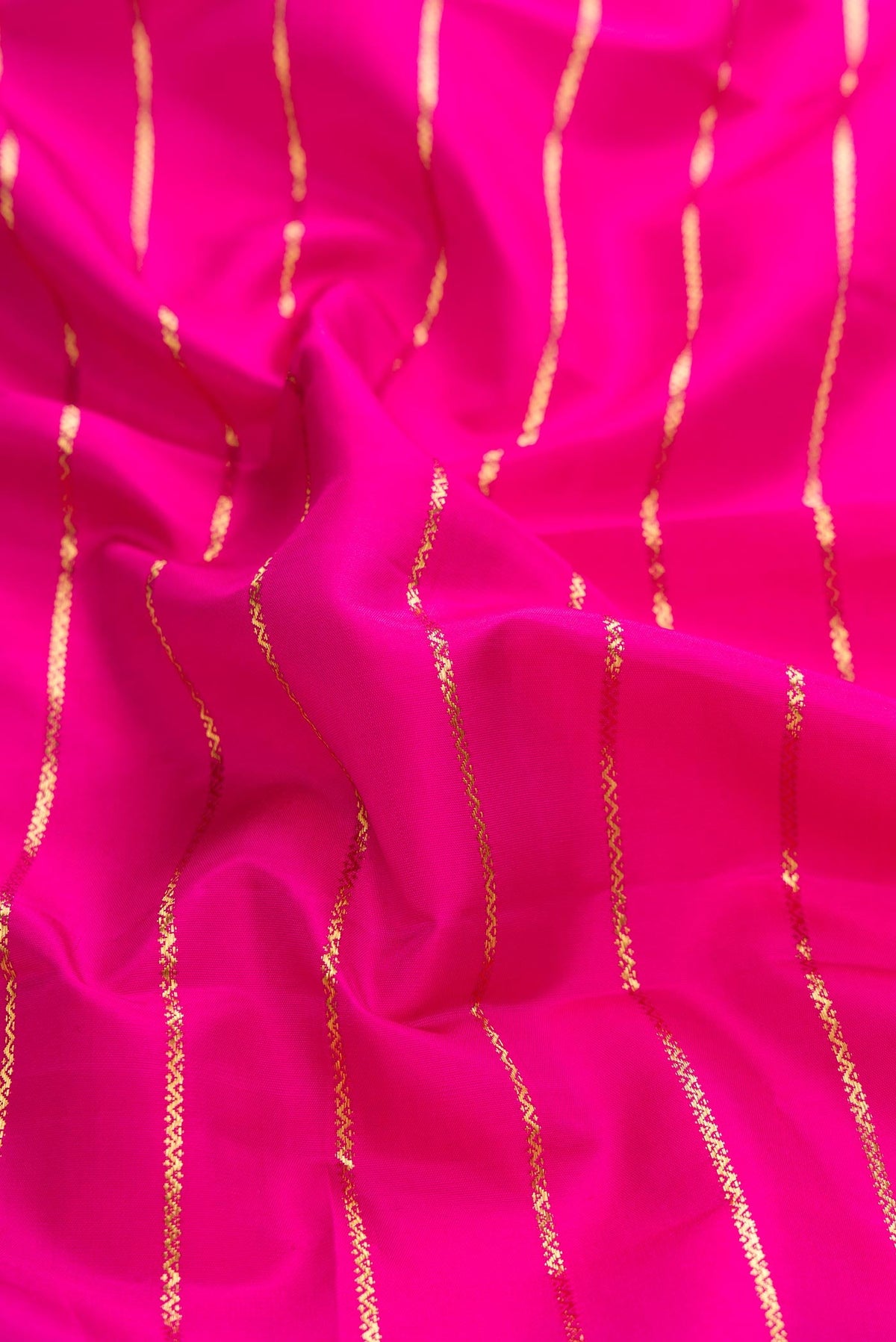 Close up of Pink Dual Tone Kanchipuram Silk Saree with Veldhari on the body and Zari Border displaying folds