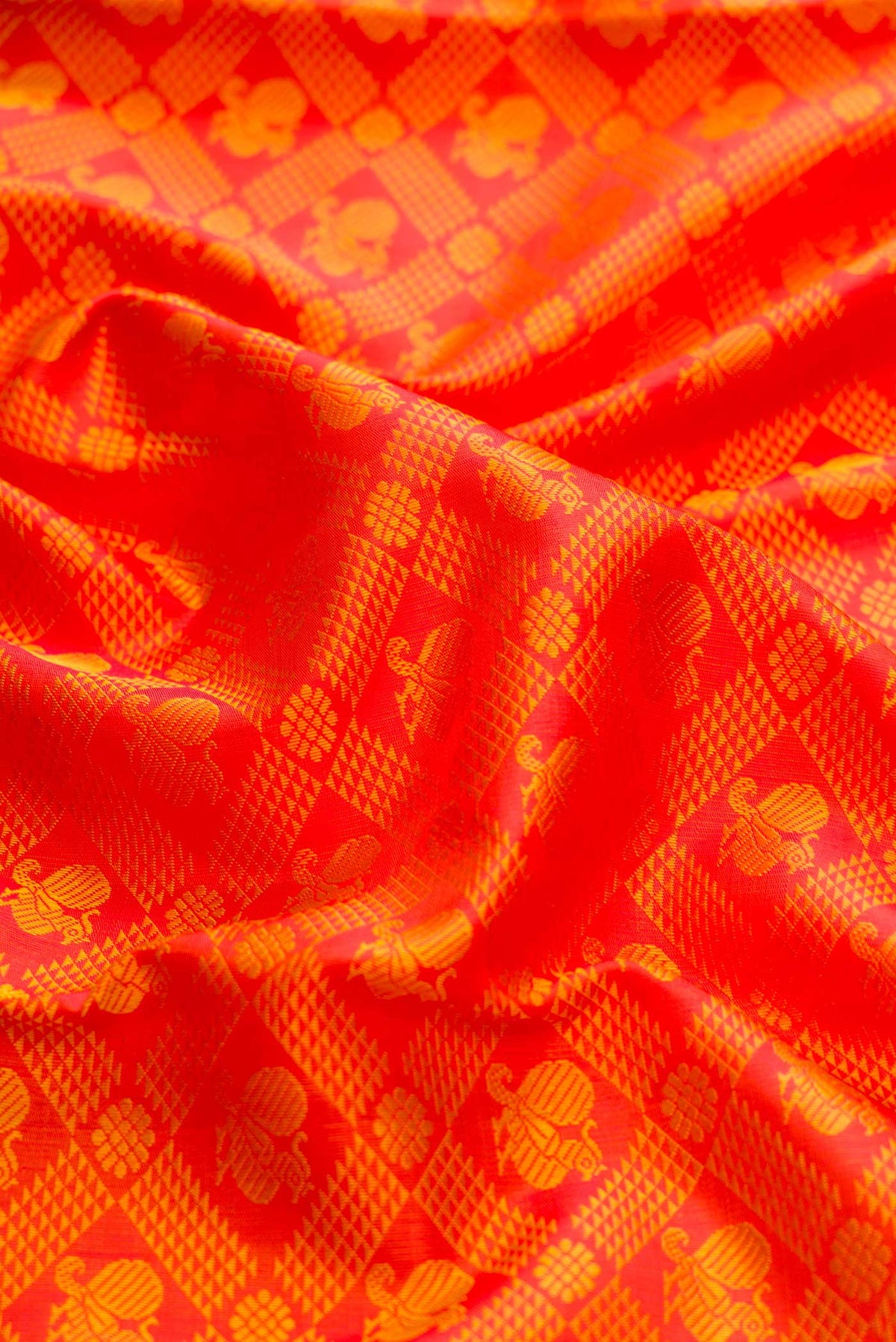 Close up of Pure Silk Pure Zari Orange Dual Tone Kanchipuram Saree with Jacquard design on the body and Zari Border displaying folds