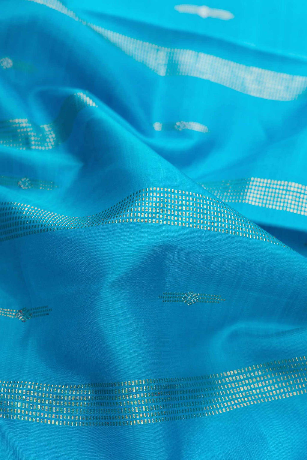 Close up of Sky Blue Dual Tone Kanchipuram Silk Saree with Zari Butta on the body and Zari Border displaying folds