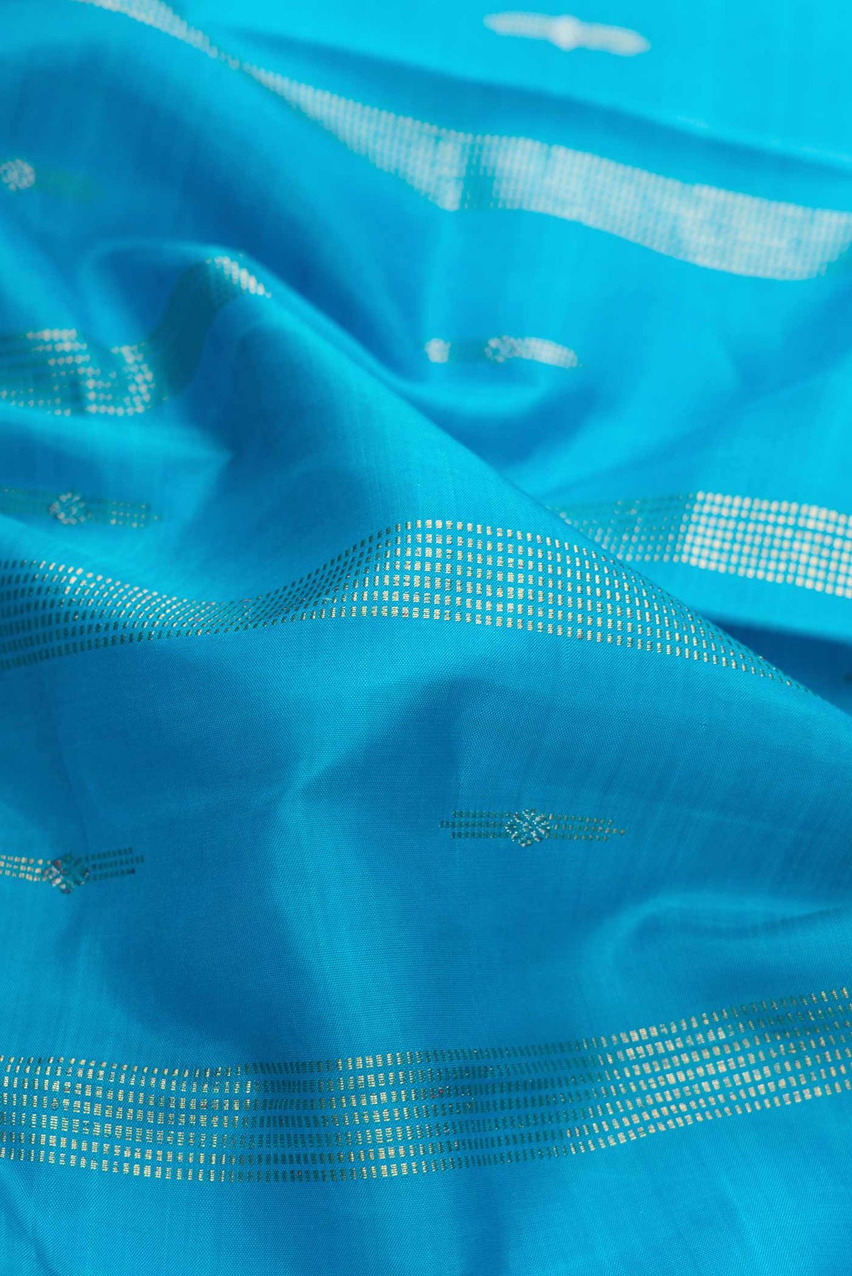 Close up of Sky Blue Dual Tone Kanchipuram Silk Saree with Zari Butta on the body and Zari Border displaying folds