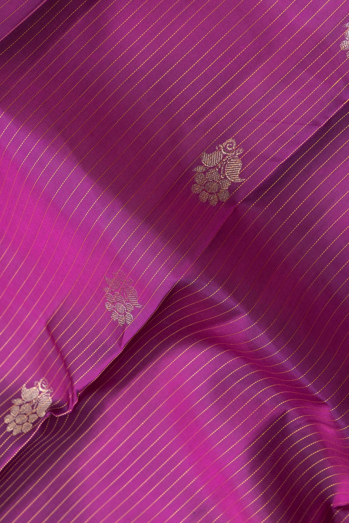 Close up of Magenta Dual Tone Kanjivaram Silk Saree with Stripes on the body and Zari Border.  displaying folds