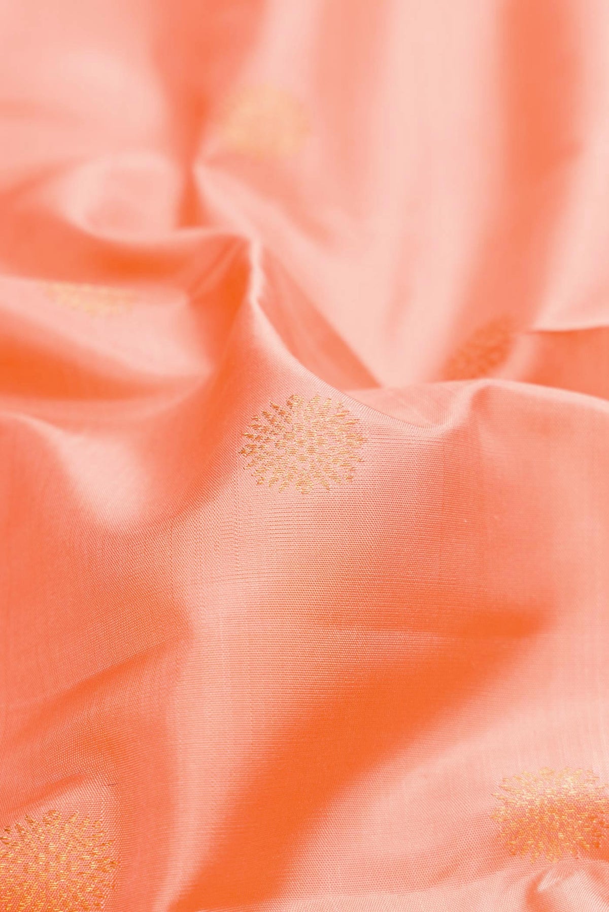 Close up of Peach Dual Tone Kanchipuram Silk Saree with Zari Butta on the body and Zari Border.  displaying folds