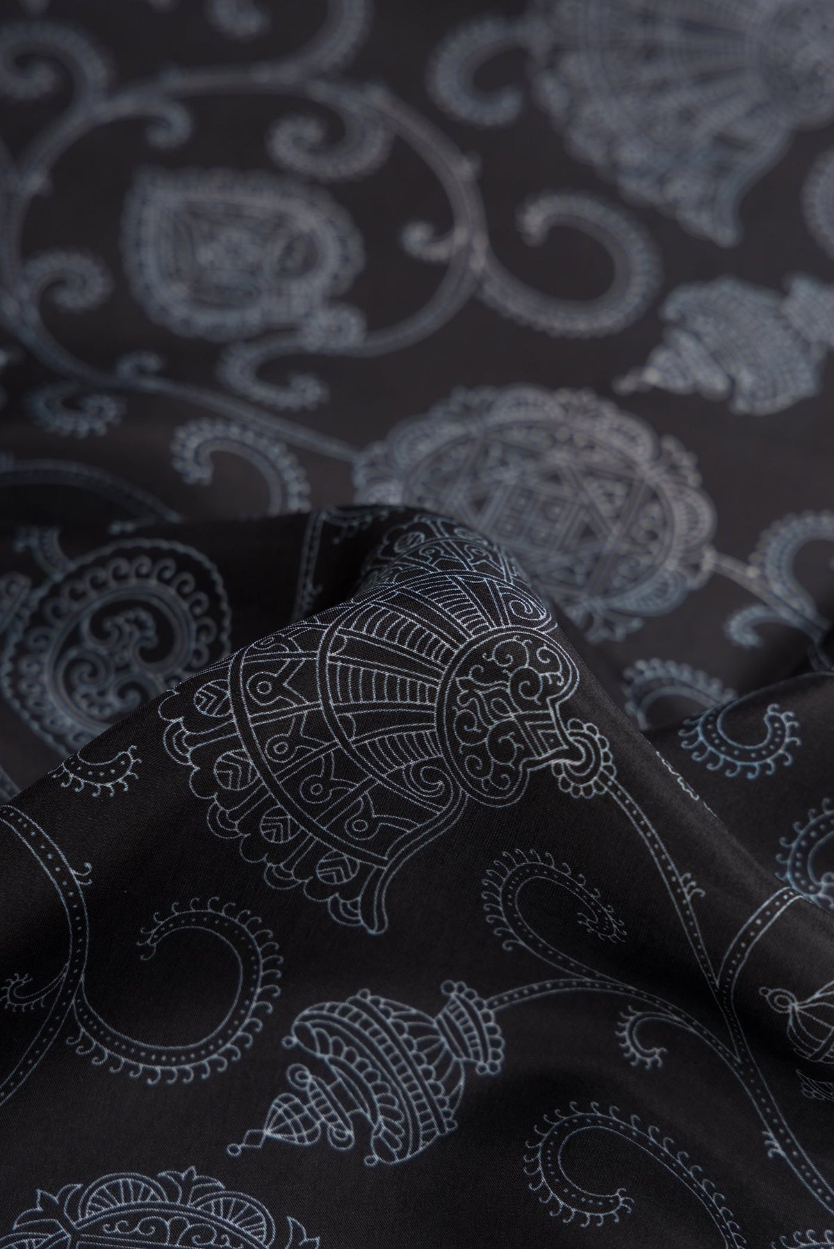 Close up of Black Dual Tone Printed Silk Saree with Printed design on the body and Plain Border.  displaying folds