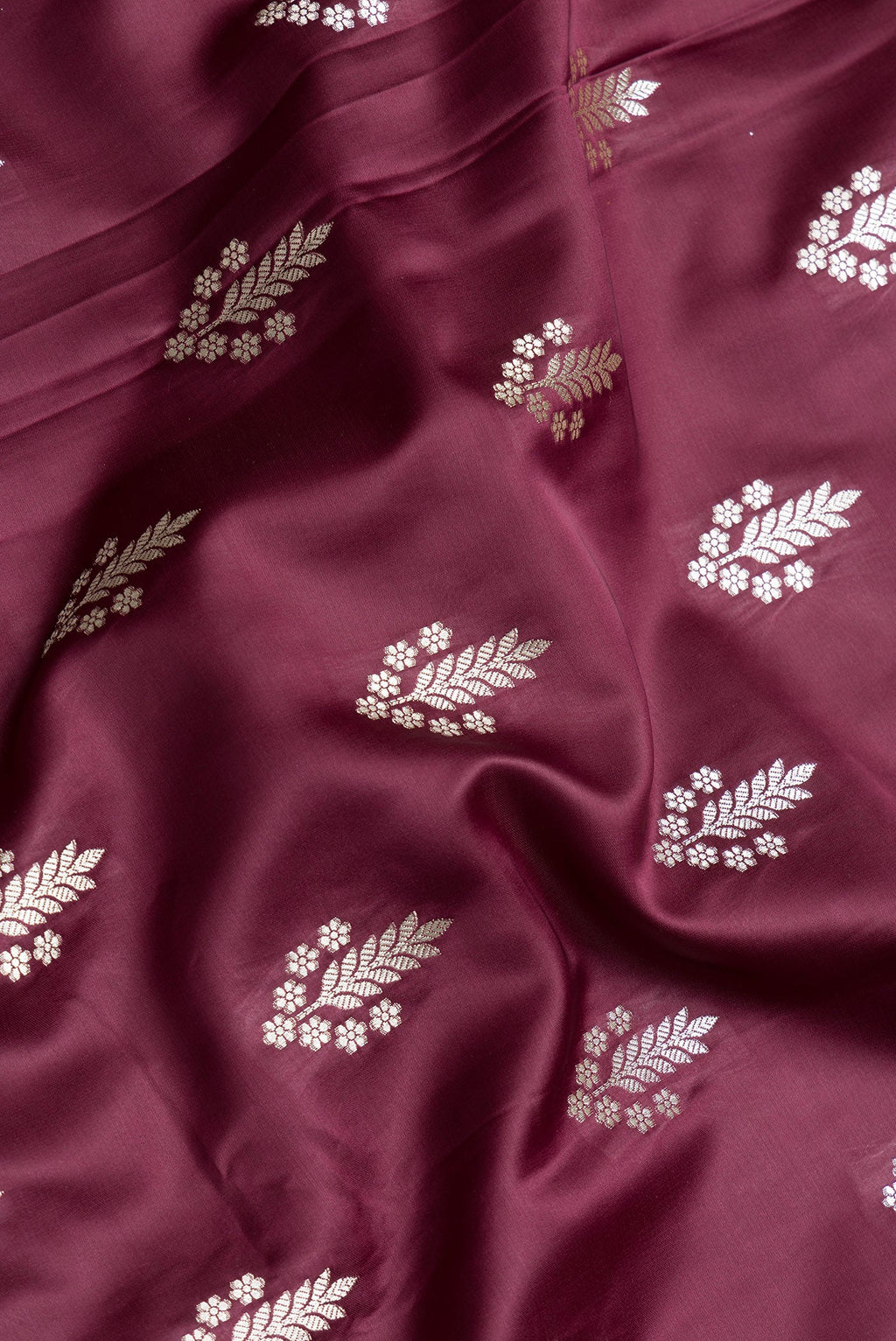 Close up of Maroon Dual Tone Banarasi Silk Saree with Zari Butta on the body and Zari Border.  displaying folds