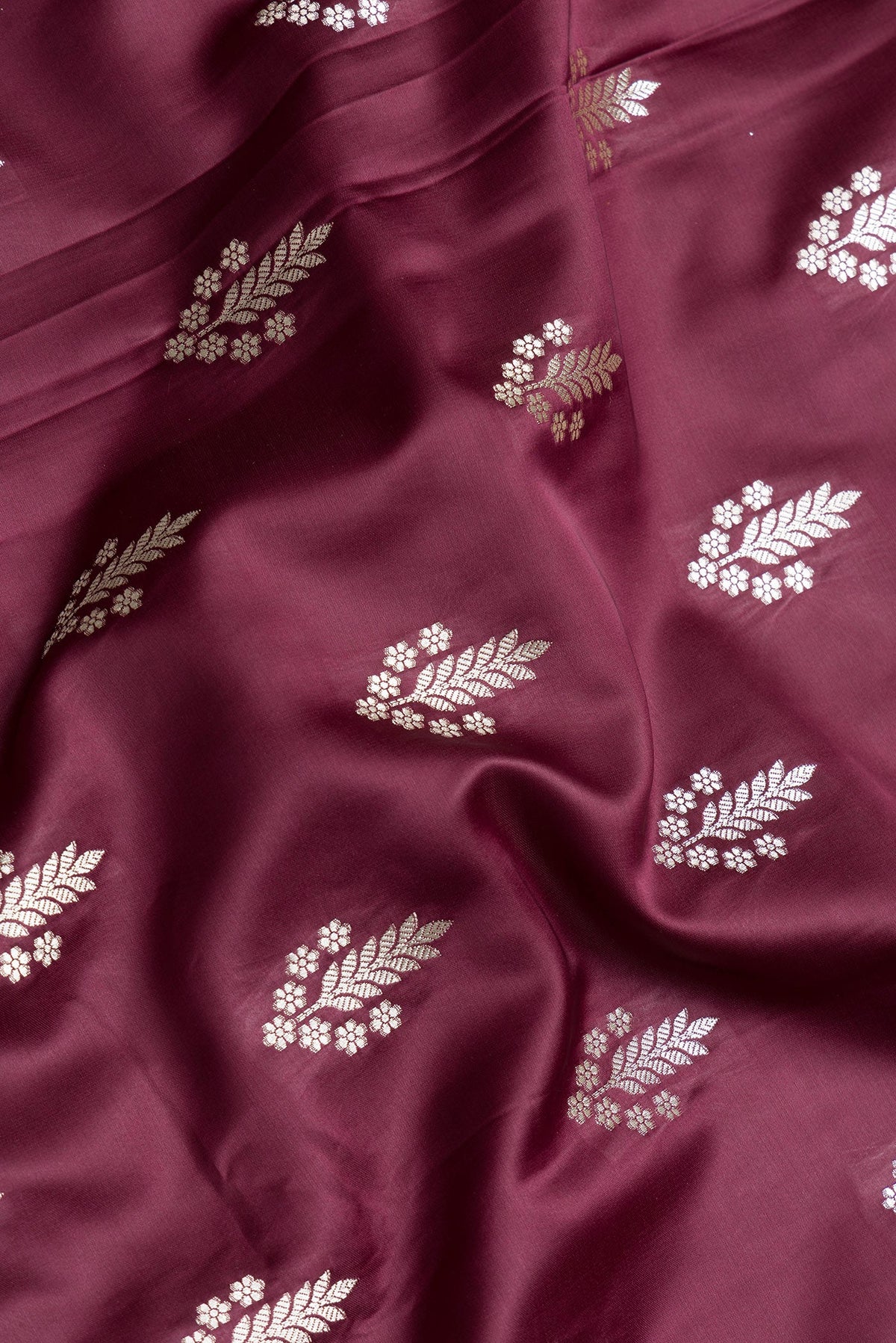 Close up of Maroon Dual Tone Banarasi Silk Saree with Zari Butta on the body and Zari Border.  displaying folds