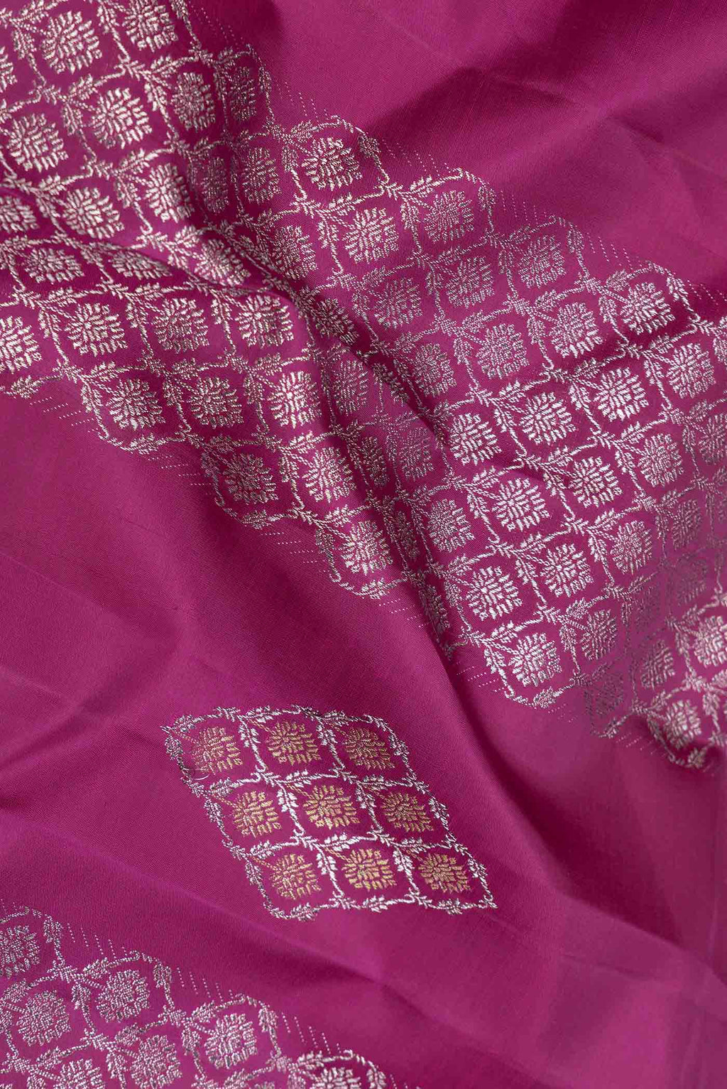 Close up of Magenta Dual Tone Kanchipuram Saree with Zari Butta on the body and Zari Border displaying folds