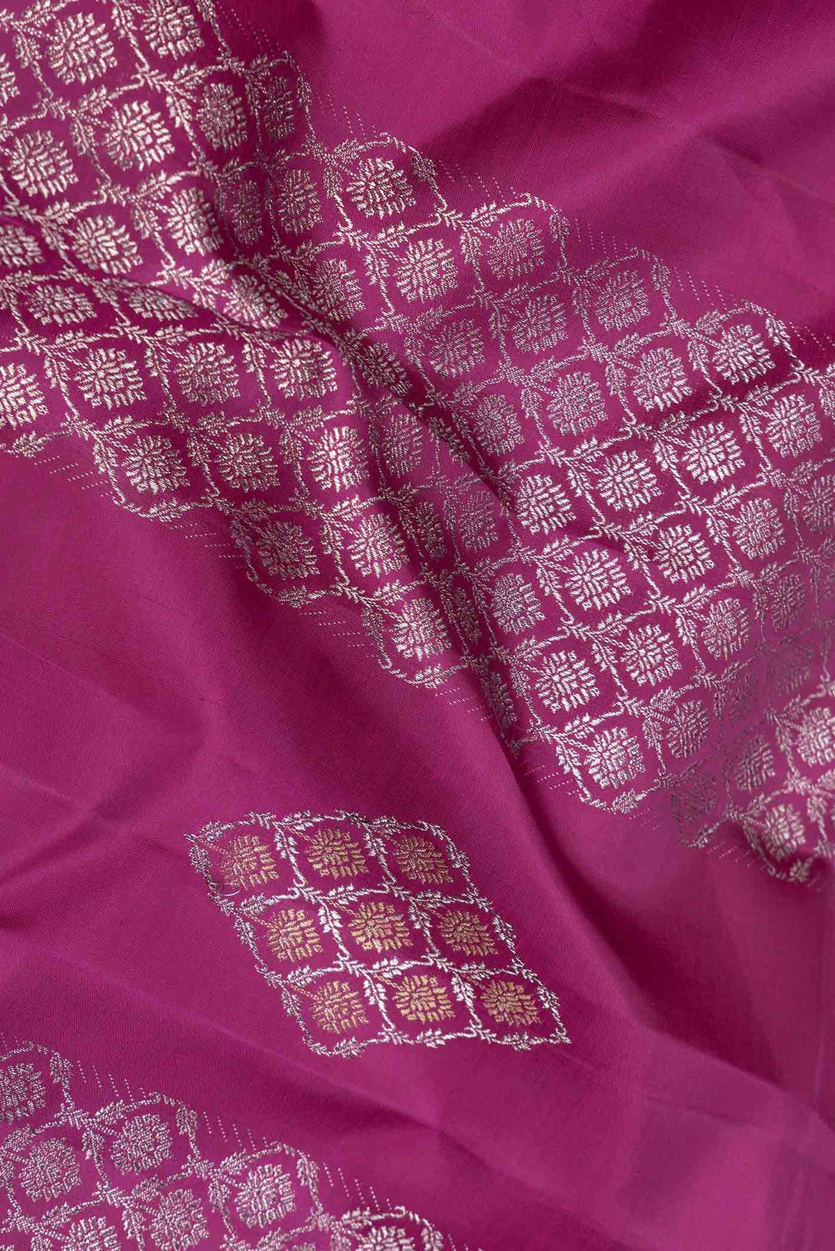 Close up of Magenta Dual Tone Kanchipuram Saree with Zari Butta on the body and Zari Border displaying folds