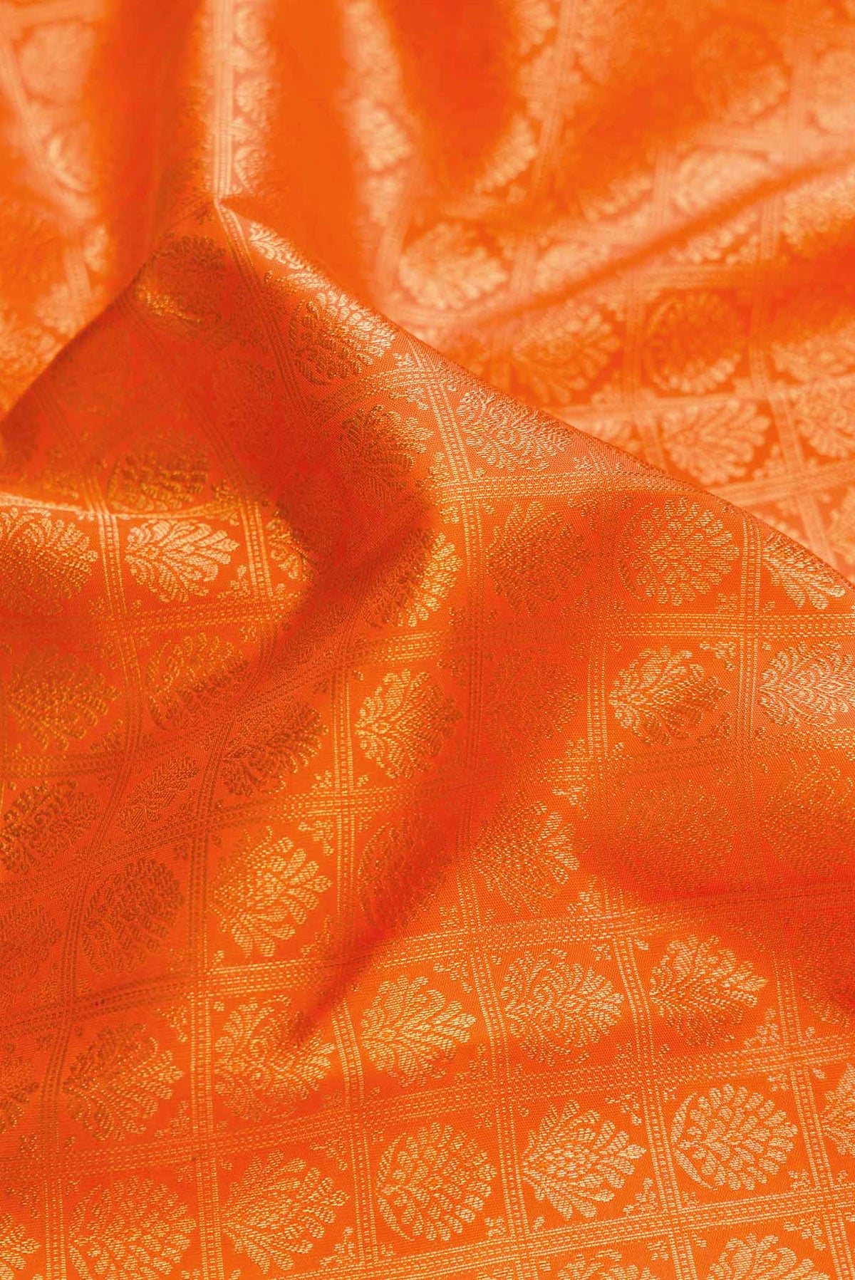 Close up of Pure Silk Pure Zari Orange Dual Tone Kanchipuram Saree with Zari Brocade on the body and Zari Border displaying folds