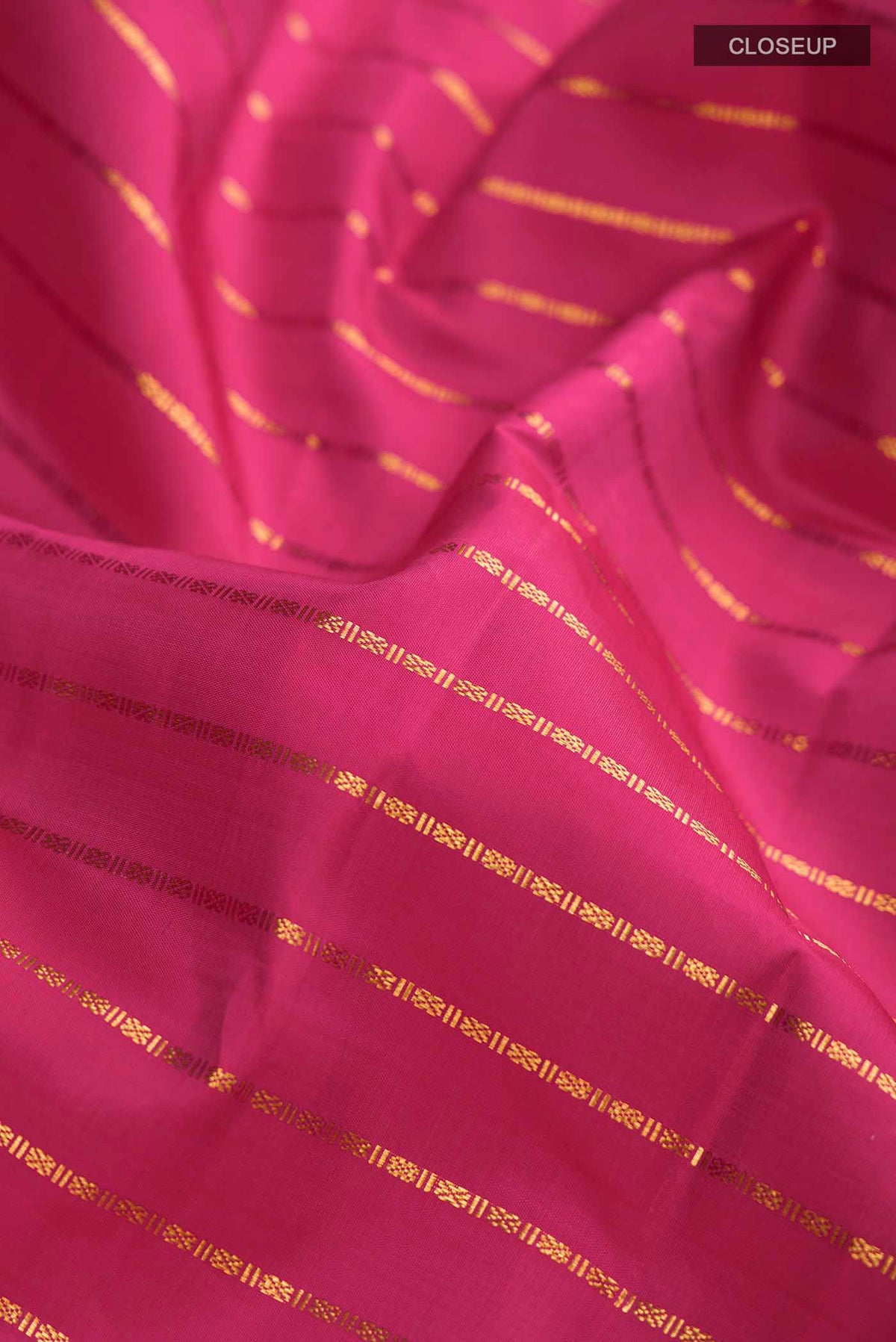 Close up of Pink Kanchipuram Silk Saree with Stripes on the body and Zari Border displaying folds