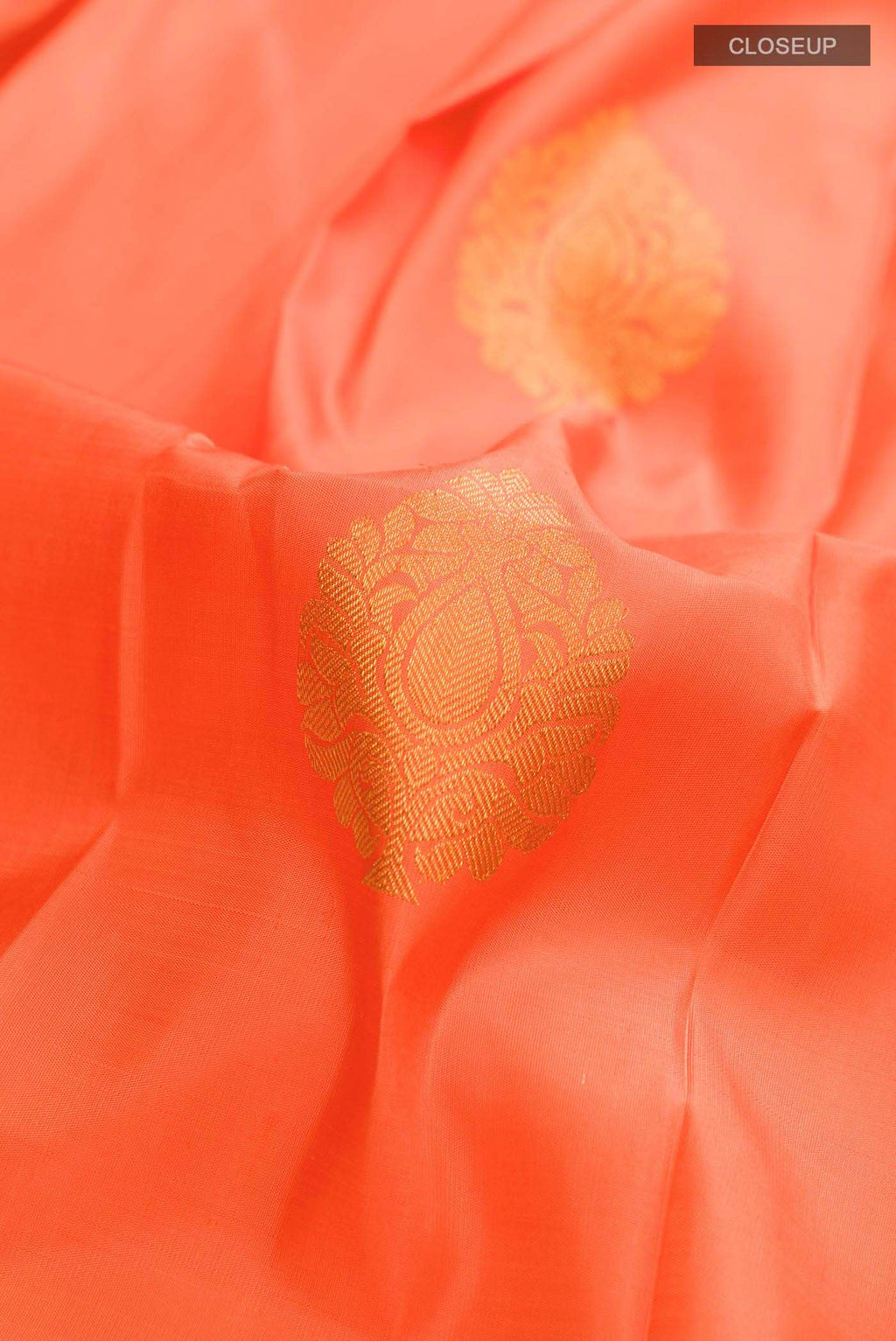 Close up of Orange Kanchipuram Silk Saree with Zari Butta on the body and Without Border displaying folds