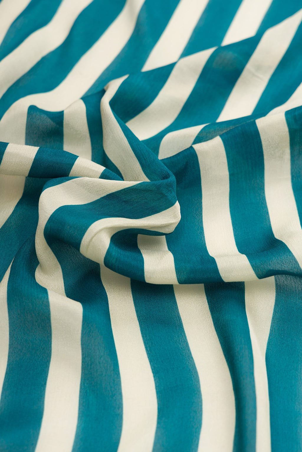 Close up of Beige and Peacock Blue Color Mysore Crepe Saree with Stripes on the body and Embroidery Border.  displaying folds