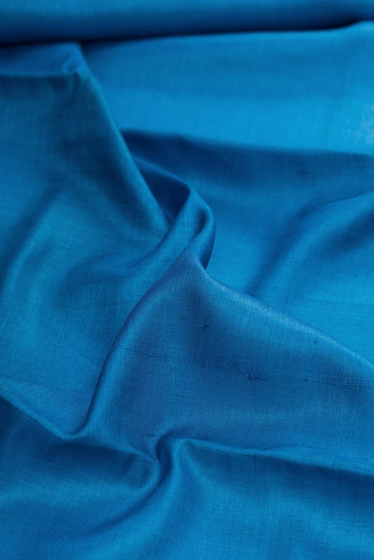 Close up of Sky Blue Dual Tone Tussar Silk Saree with Plain Body and Printed Border.  displaying folds