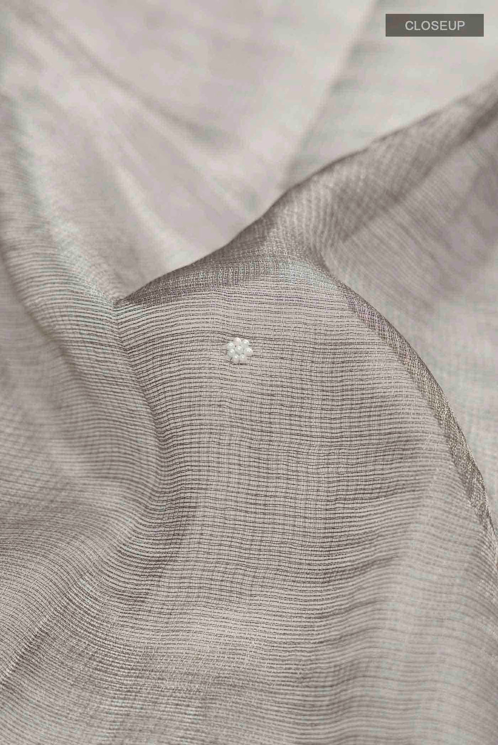 Close up of Grey Tissue Silk Saree with Embroidery on the body and Embroidery Border displaying folds