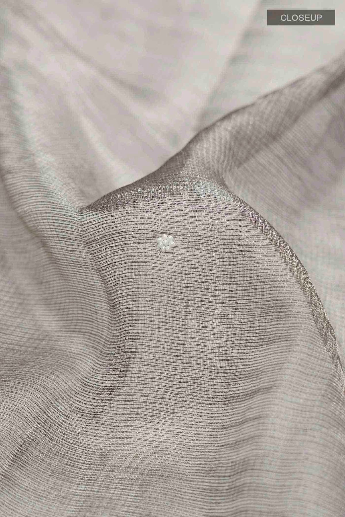 Close up of Grey Tissue Silk Saree with Embroidery on the body and Embroidery Border displaying folds